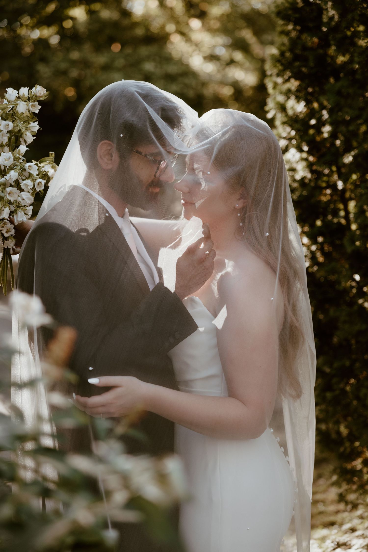 A romantic wedding moment captured through a delicate veil in golden sunlight.