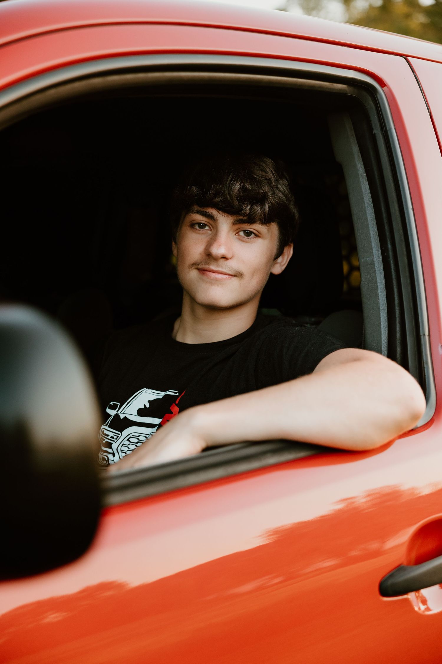 Red vintage car with person visible through driver's side window.