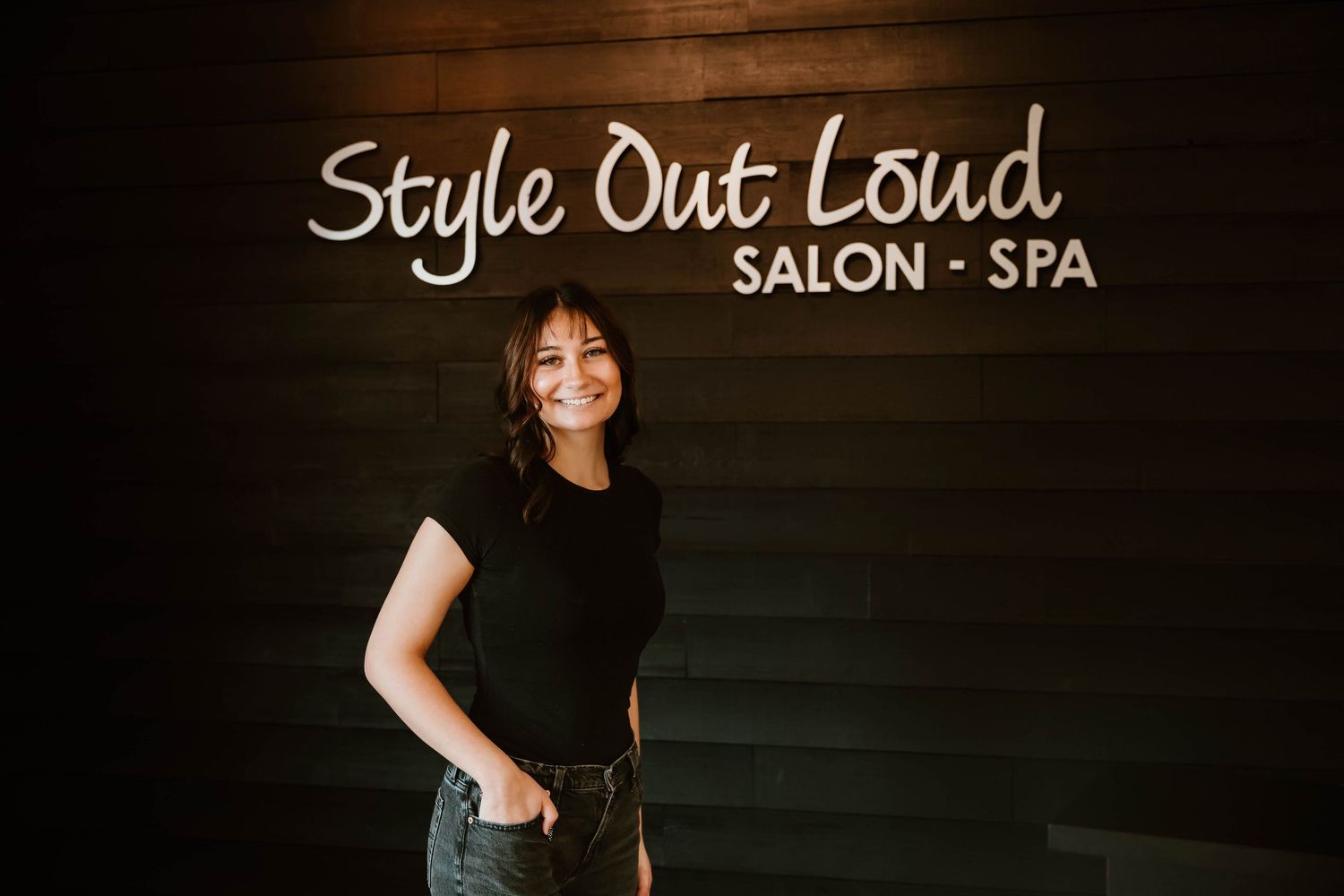 Salon interior with 'Style Out Loud' signage and dark wood paneling.