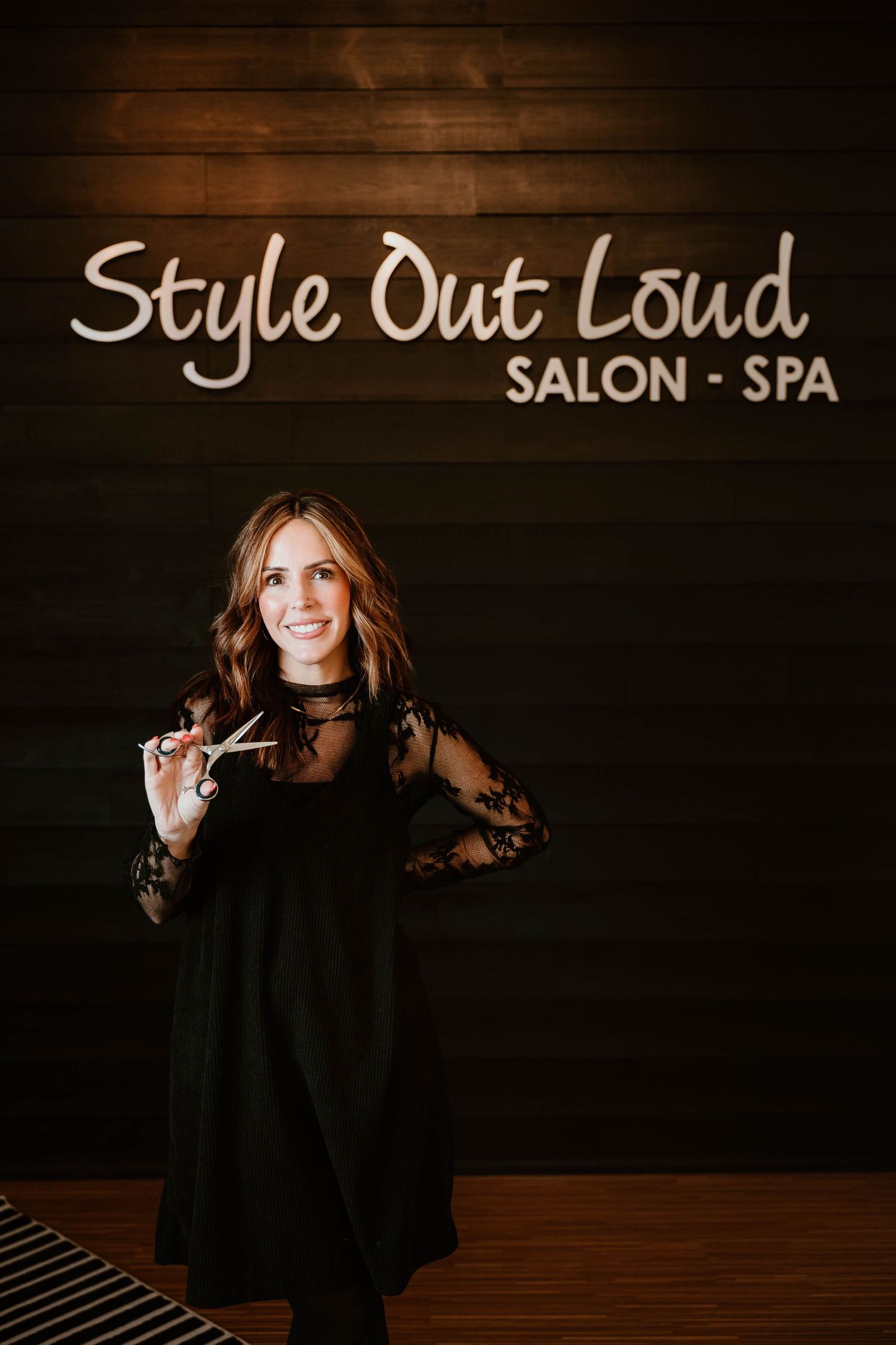 Stylish portrait session at Style Out Loud salon featuring dark wood backdrop.