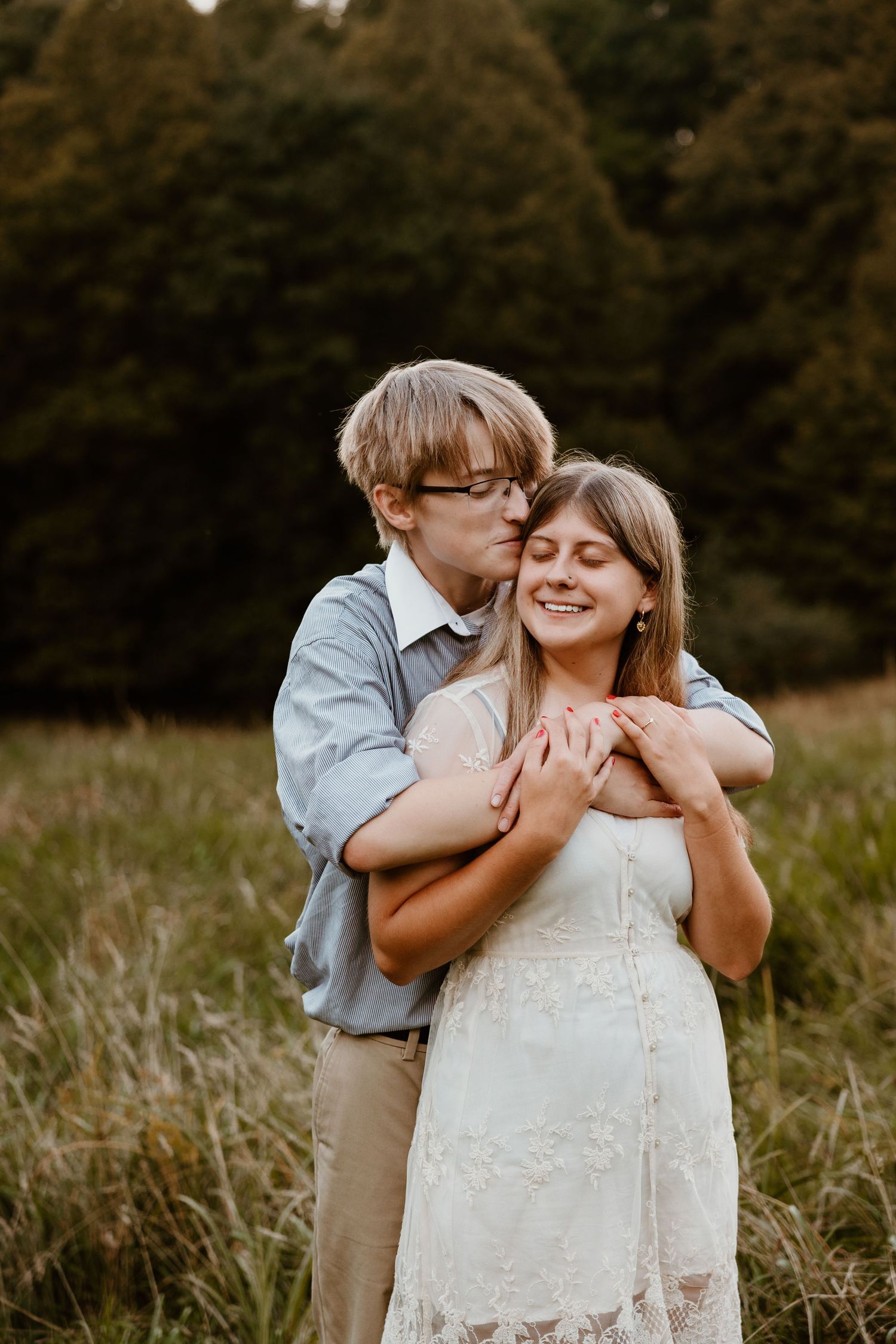 A tender moment between a couple in a sunlit meadow.