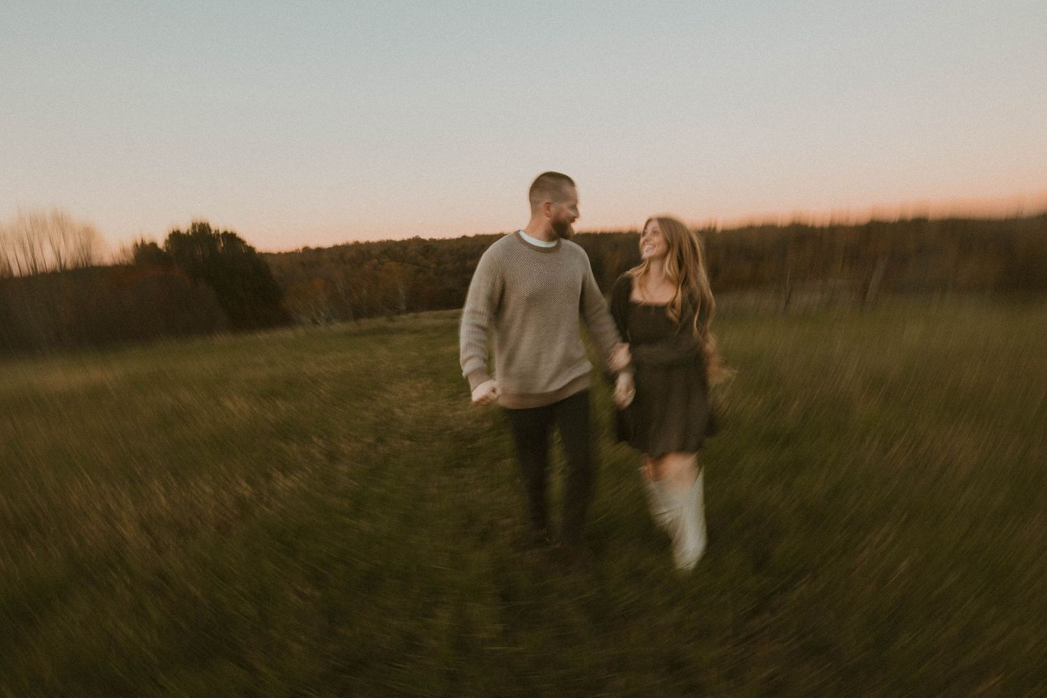 Silhouettes walking through golden field at sunset in panoramic sequence.