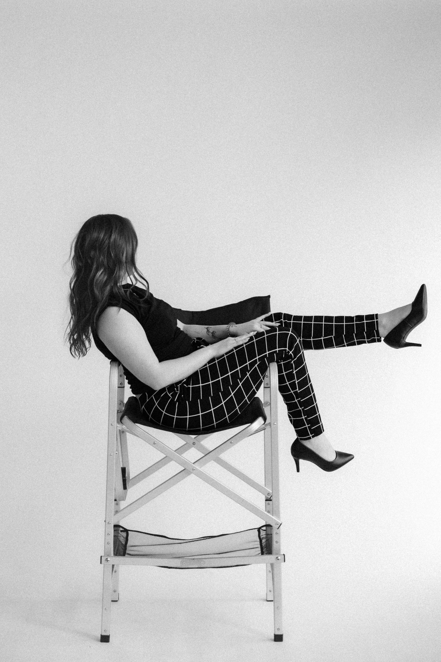 Artistic black and white portrait series showing person reclining in director's chair.