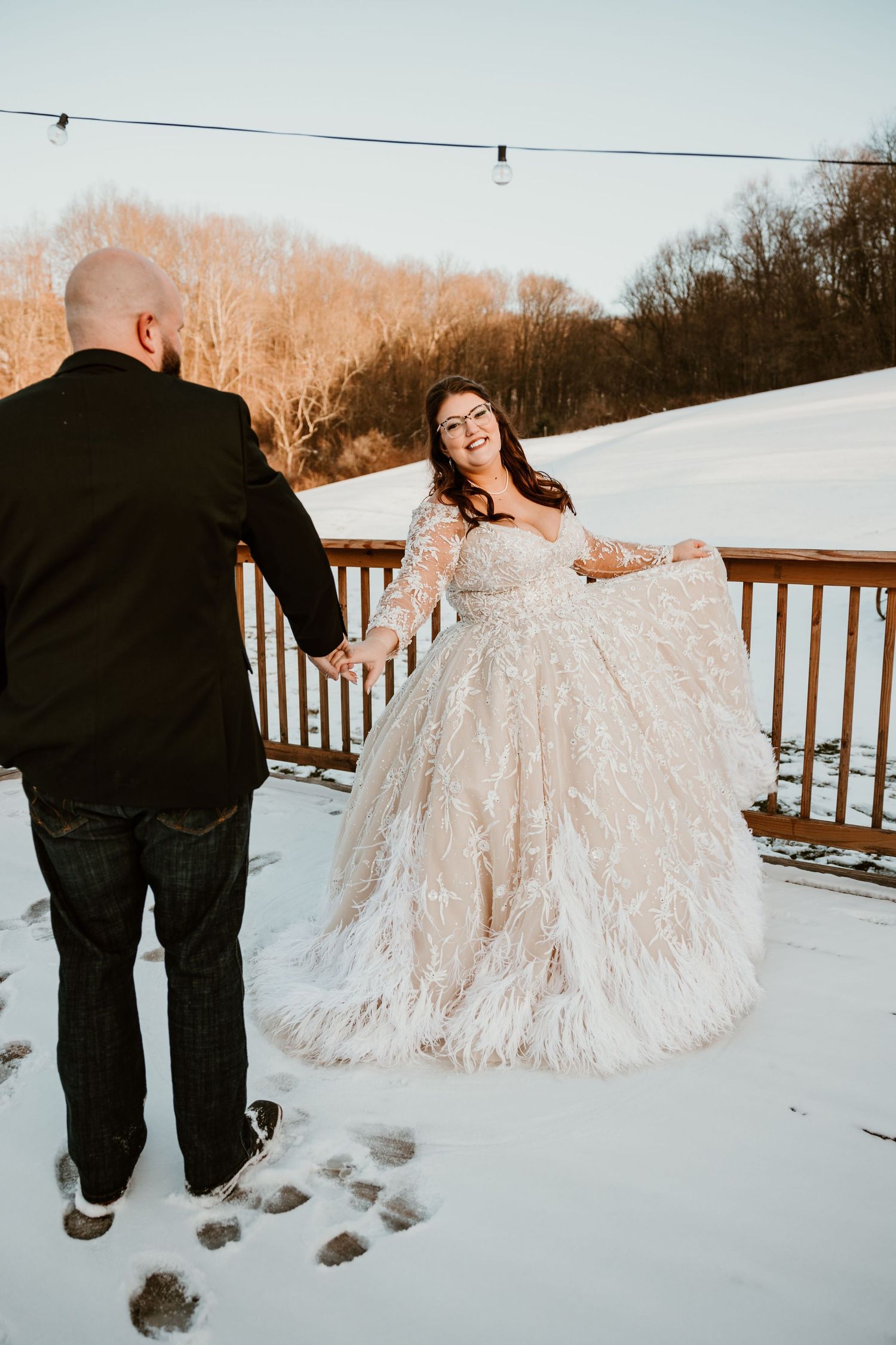 Wedding couple walking through snow-covered landscape in formal attire.