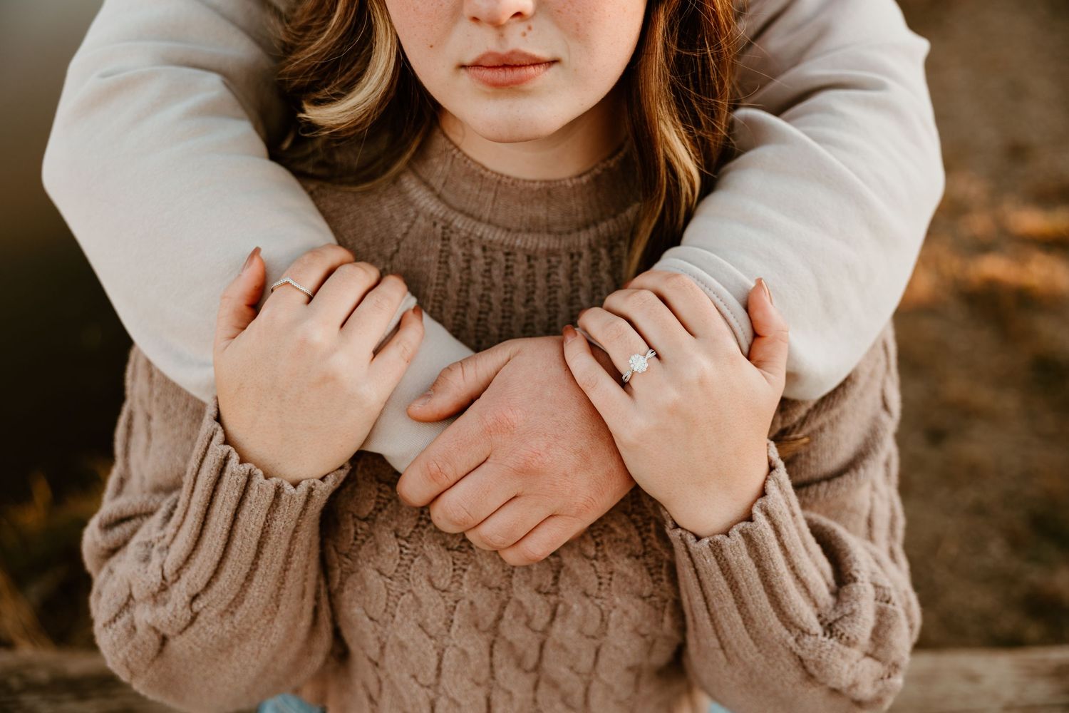 Close-up of hands embracing in a cozy cable knit sweater showing intimate connection.