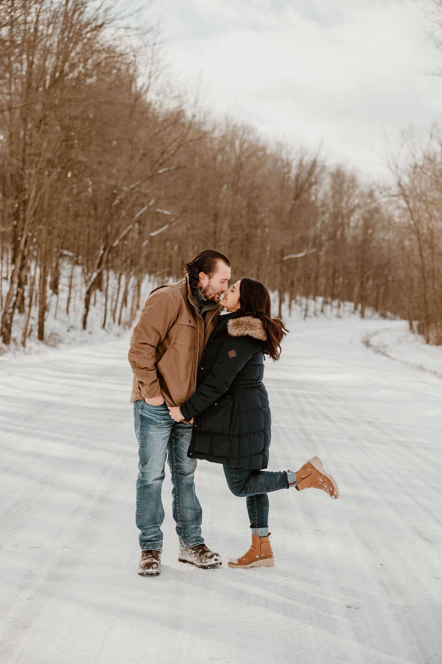 A couple shares a romantic moment on a snow-covered path in winter.