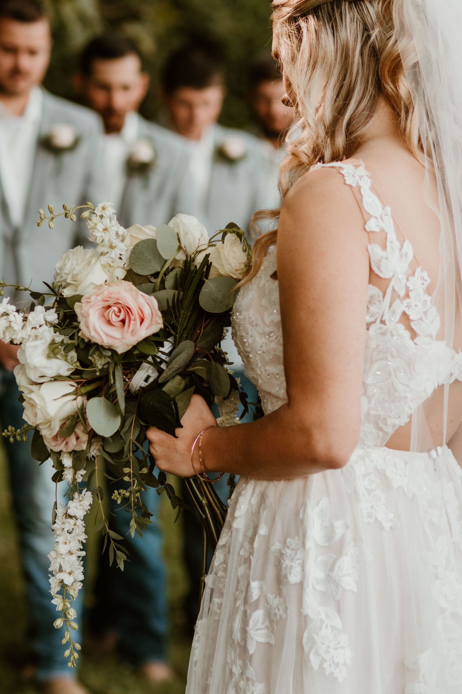 Elegant white wedding dress with lace details and pink rose bouquet.