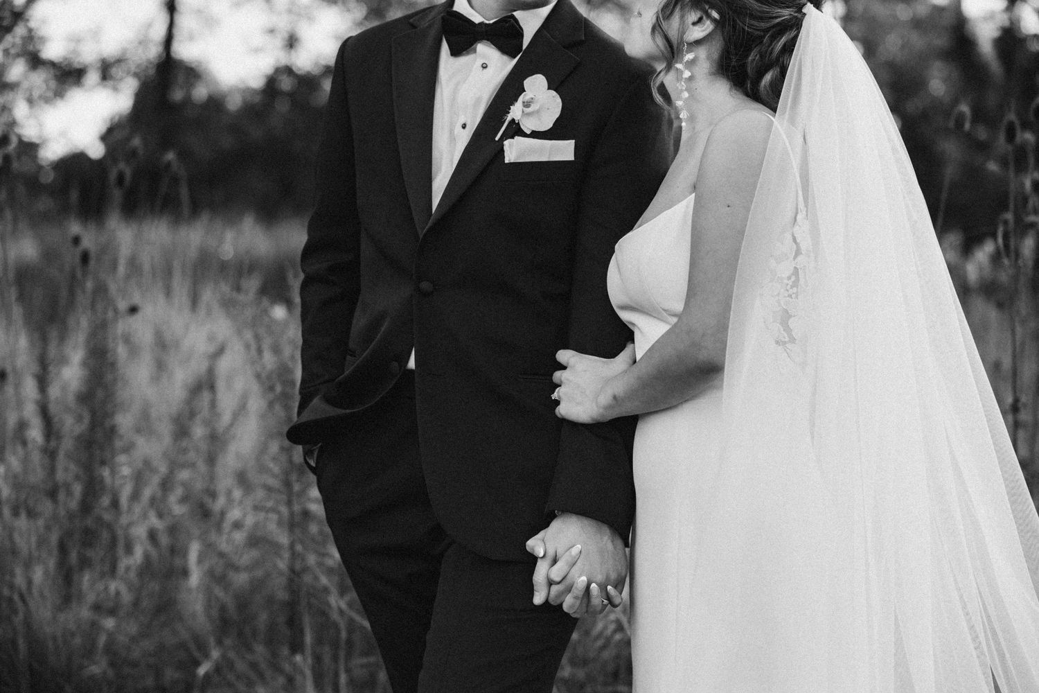 Elegant couple in wedding attire standing together in outdoor setting.