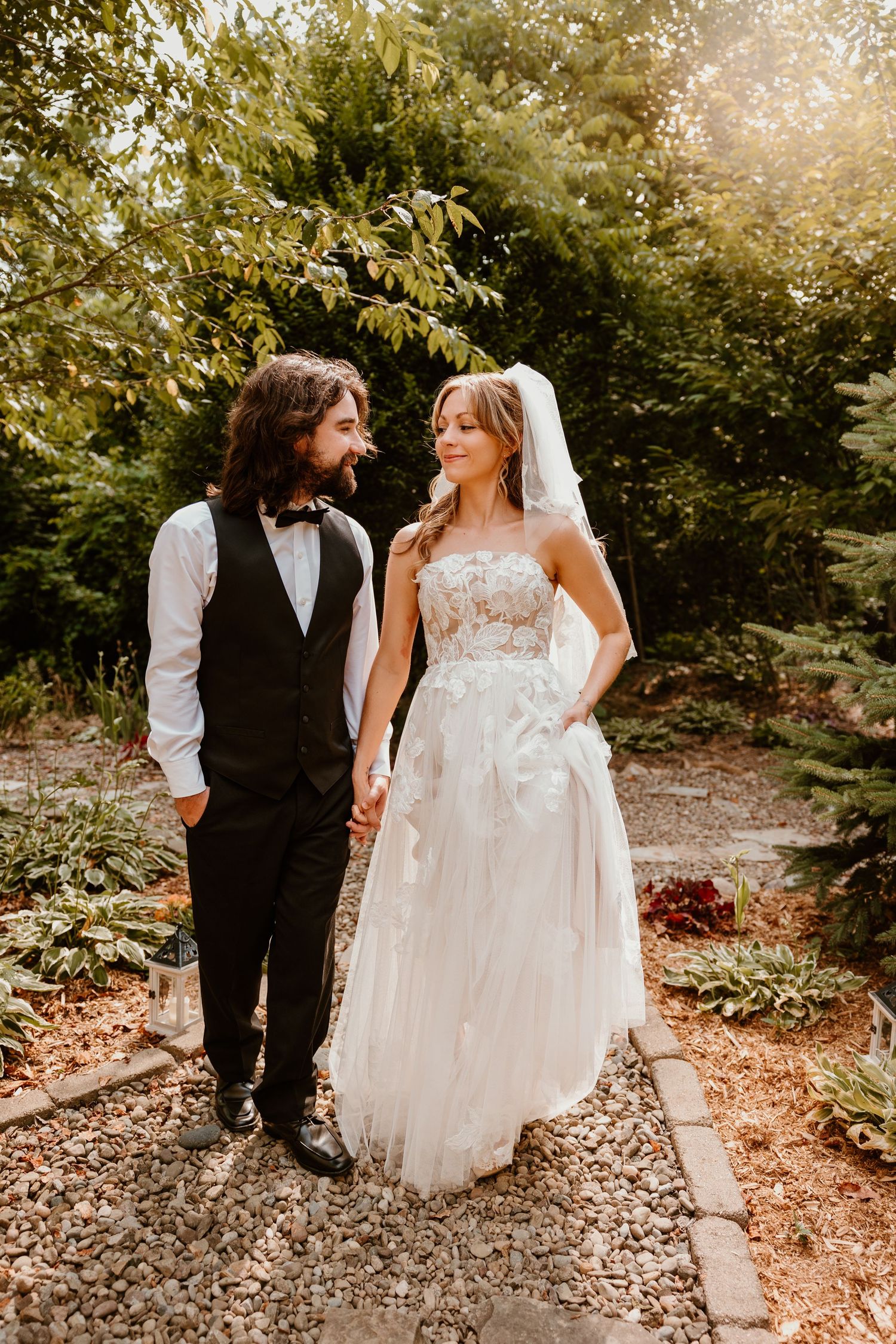 A couple shares an intimate moment on a garden path during their wedding day.