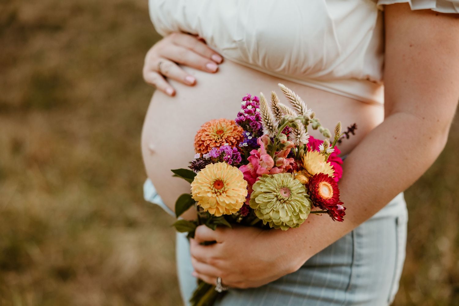 Close-up details of a maternity shoot featuring vibrant wildflowers against a natural outdoor setting.
