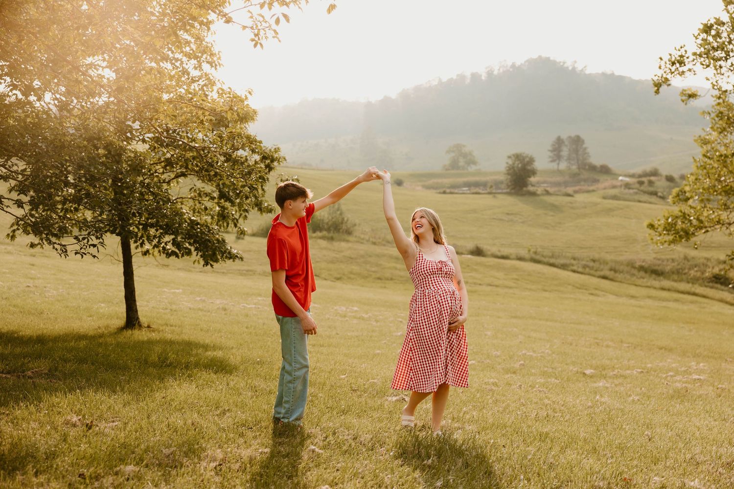 Couple walking through golden sunlit field during sunset photoshoot.