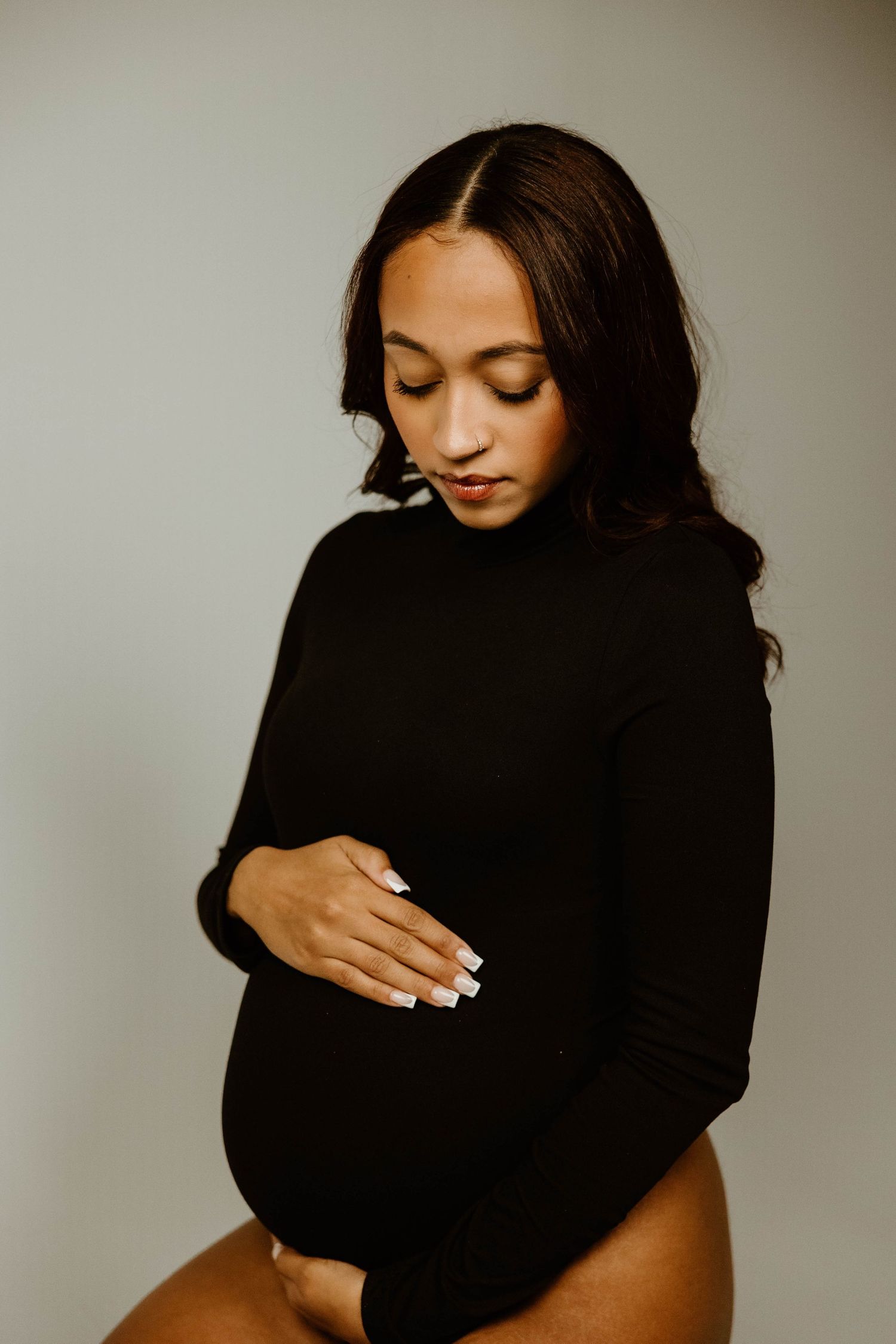 A series of artistic portrait photos showing a person in a black sweater against a neutral background.