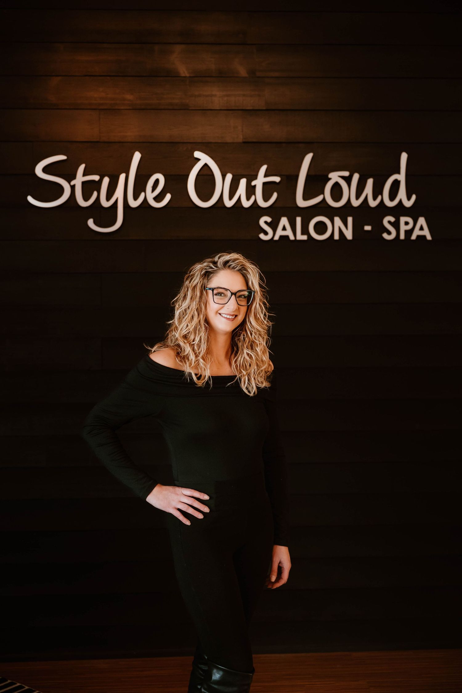 Stylish salon interior photo featuring dark wood wall with illuminated business signage.