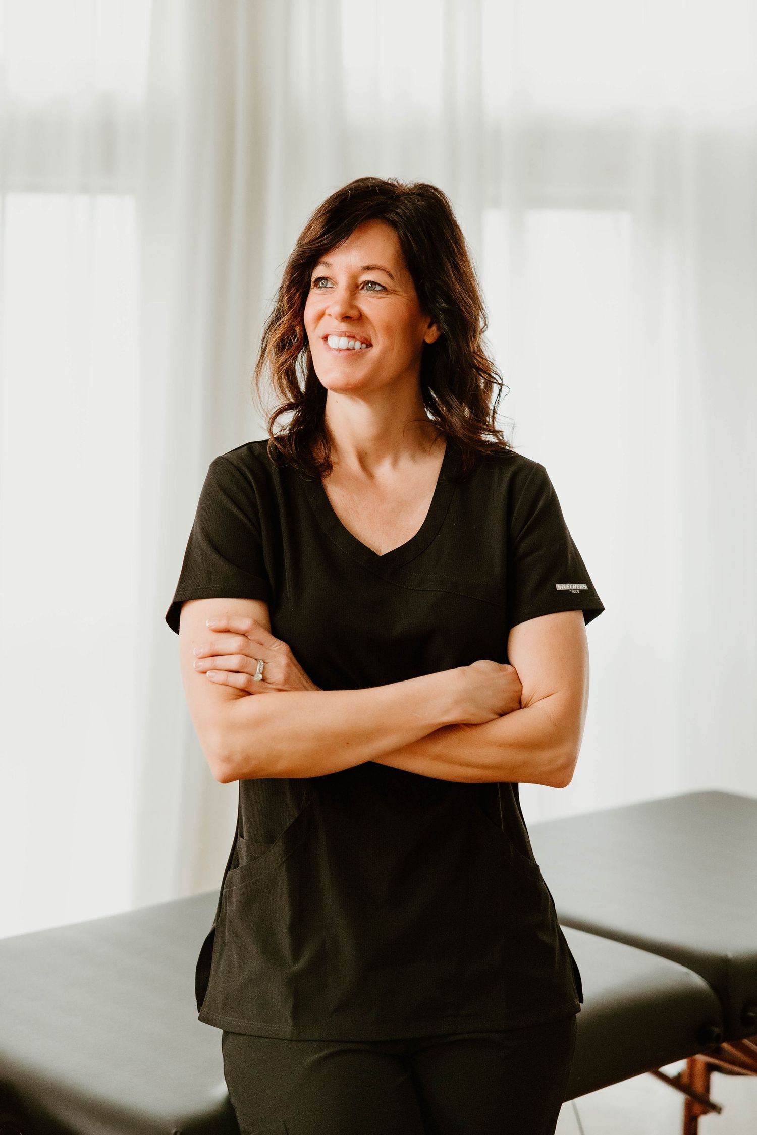 Woman in black top smiling and posing against white background in casual portrait series.