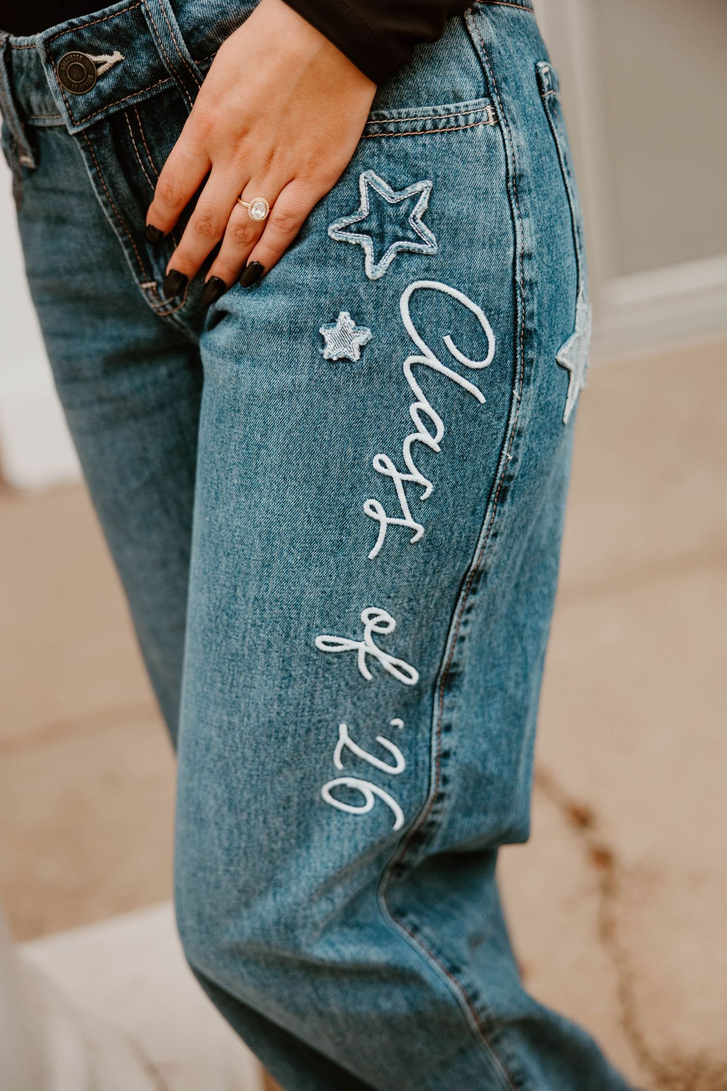 Close-up of denim jeans with star designs and writing drawn on them.