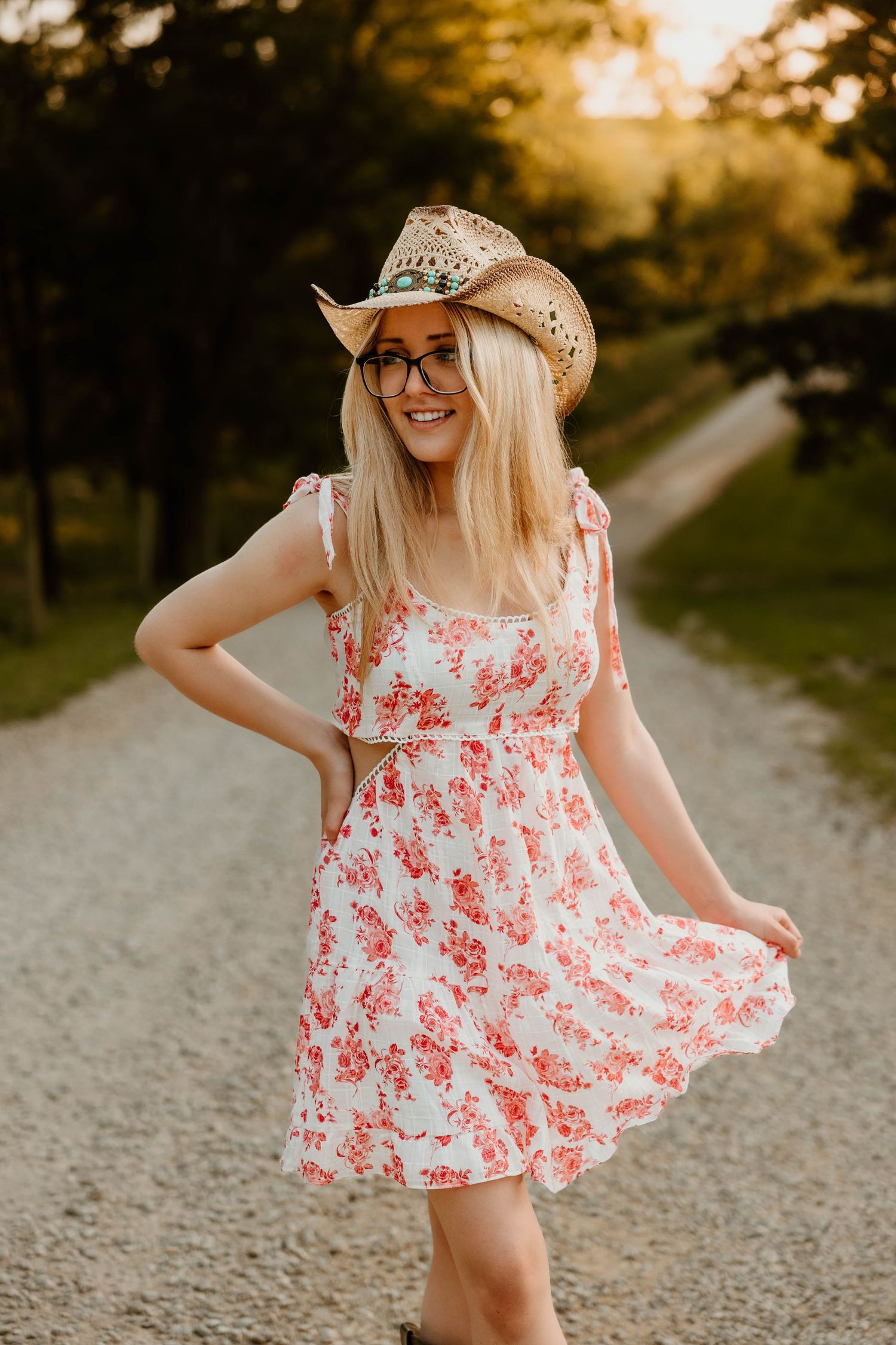 Playful outdoor photoshoot featuring floral dress and cowboy hat in sunset lighting.