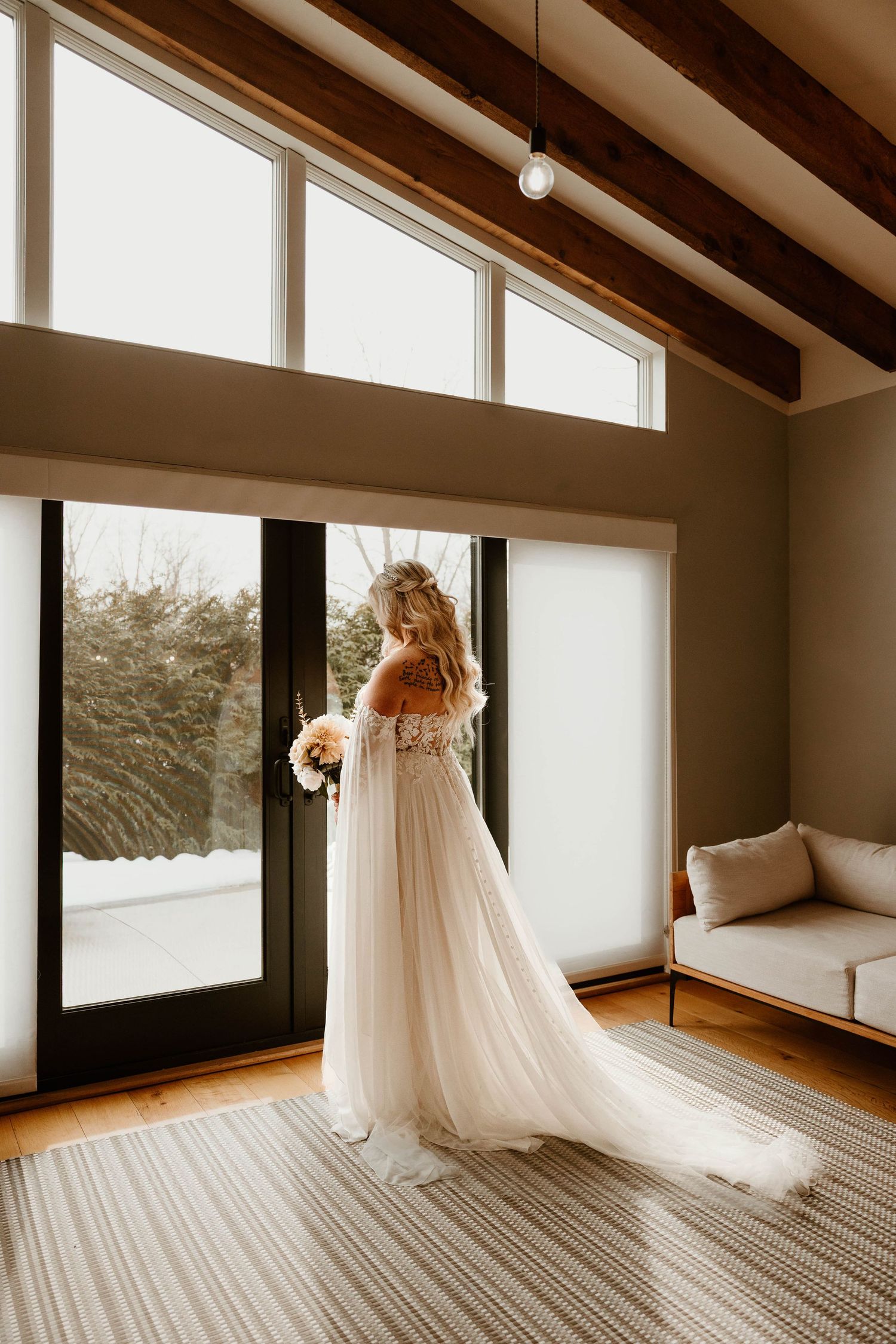 Wedding dress details in modern venue with large windows and natural light.