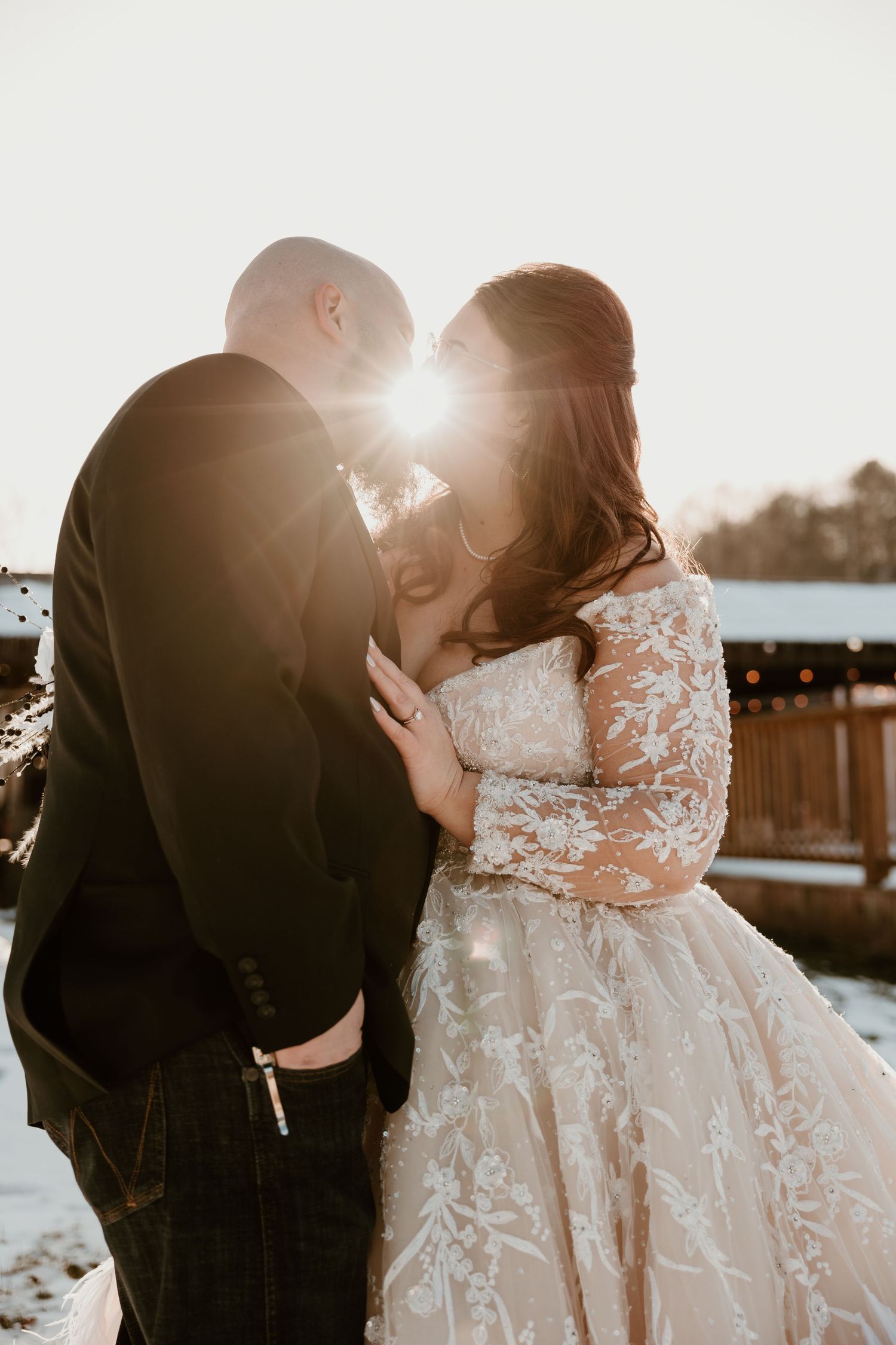 Romantic winter wedding moment captured at sunset with snow in the background.
