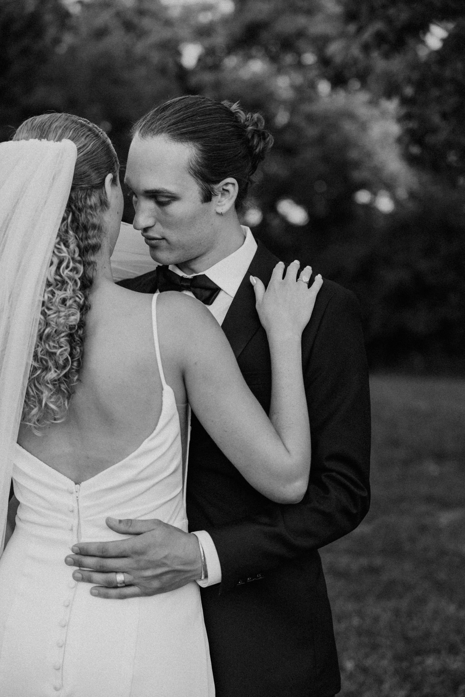 Black and white wedding portrait captures an intimate embrace between newlyweds.