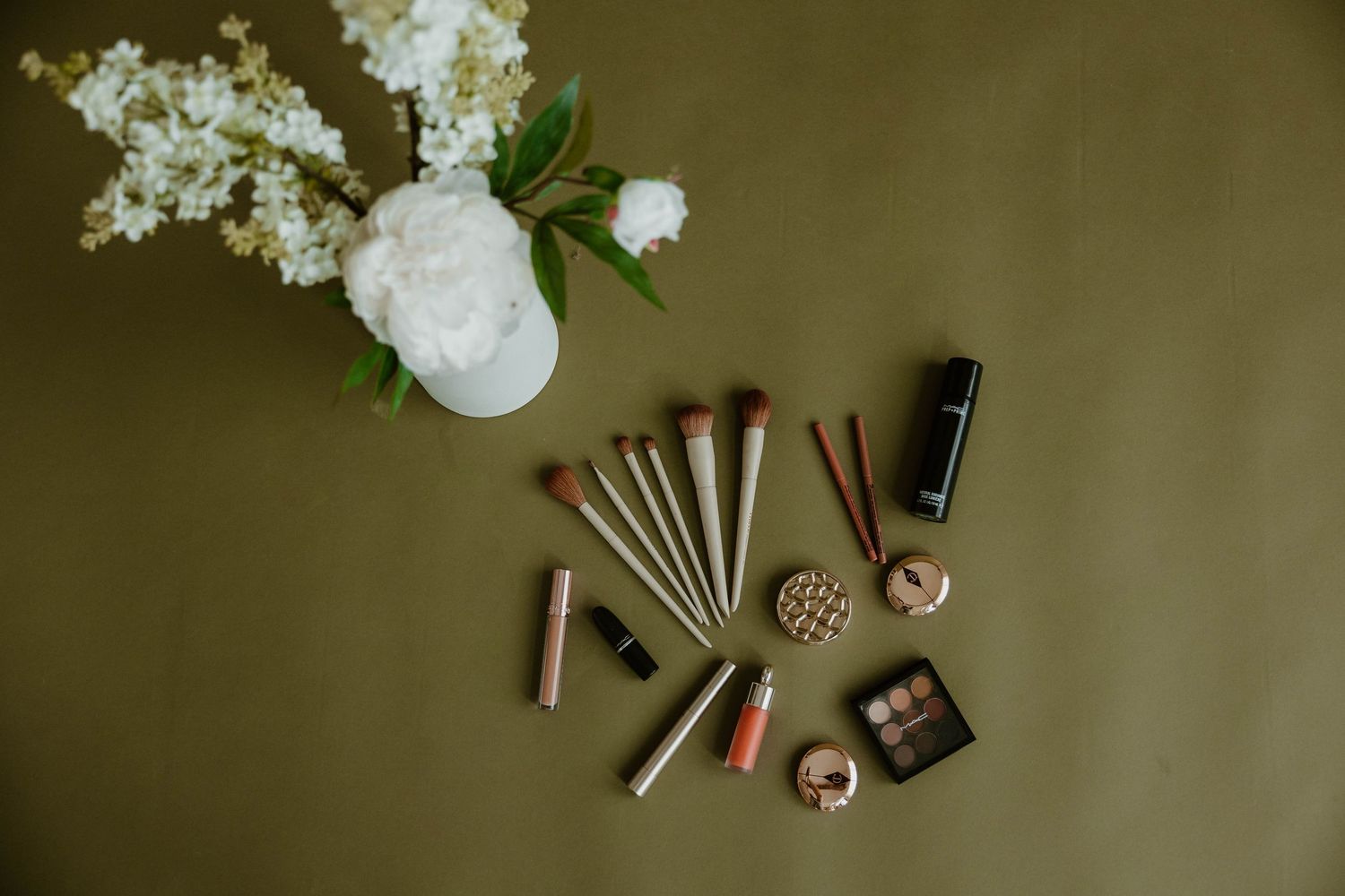 Artistic flatlay of white flowers and scattered bullet shells on dark surface.