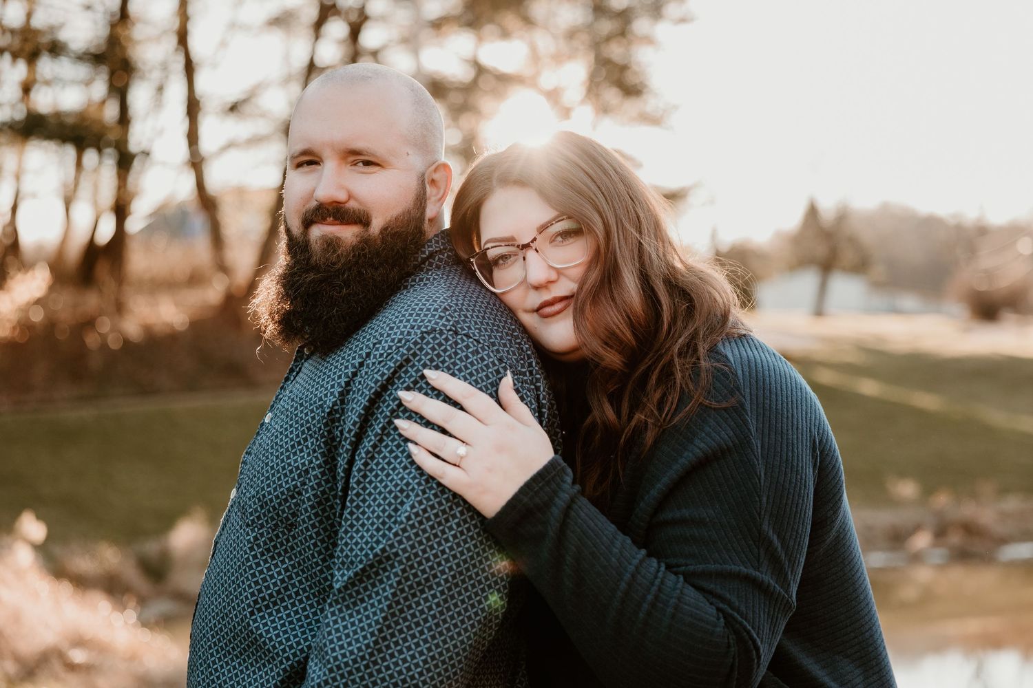 A happy couple shares a warm embrace outdoors on a sunny day.
