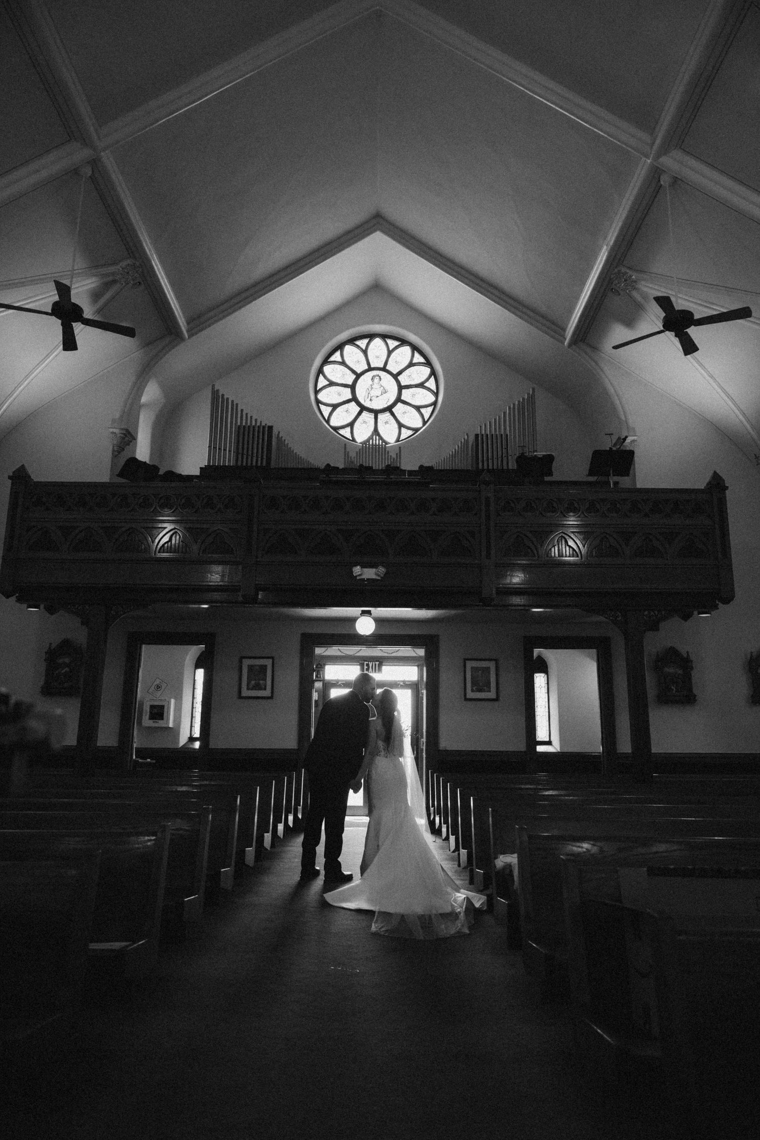 Dramatic black and white photo of a church interior with sunlight streaming through windows.