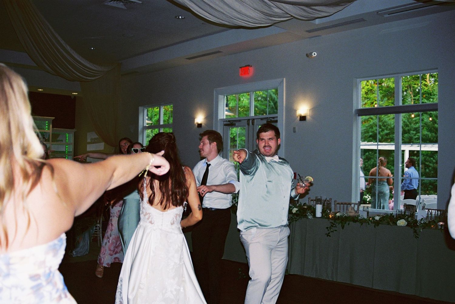 Wedding guests dancing energetically on the dance floor at a reception in an elegant ballroom venue.