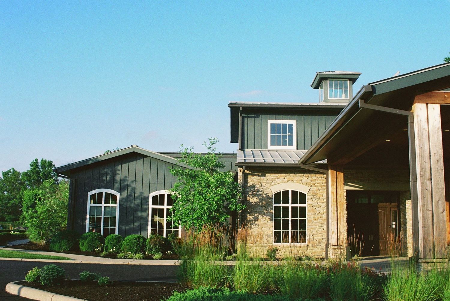 Rustic wedding venue with stone and gray barn-style architecture under a clear blue sky.