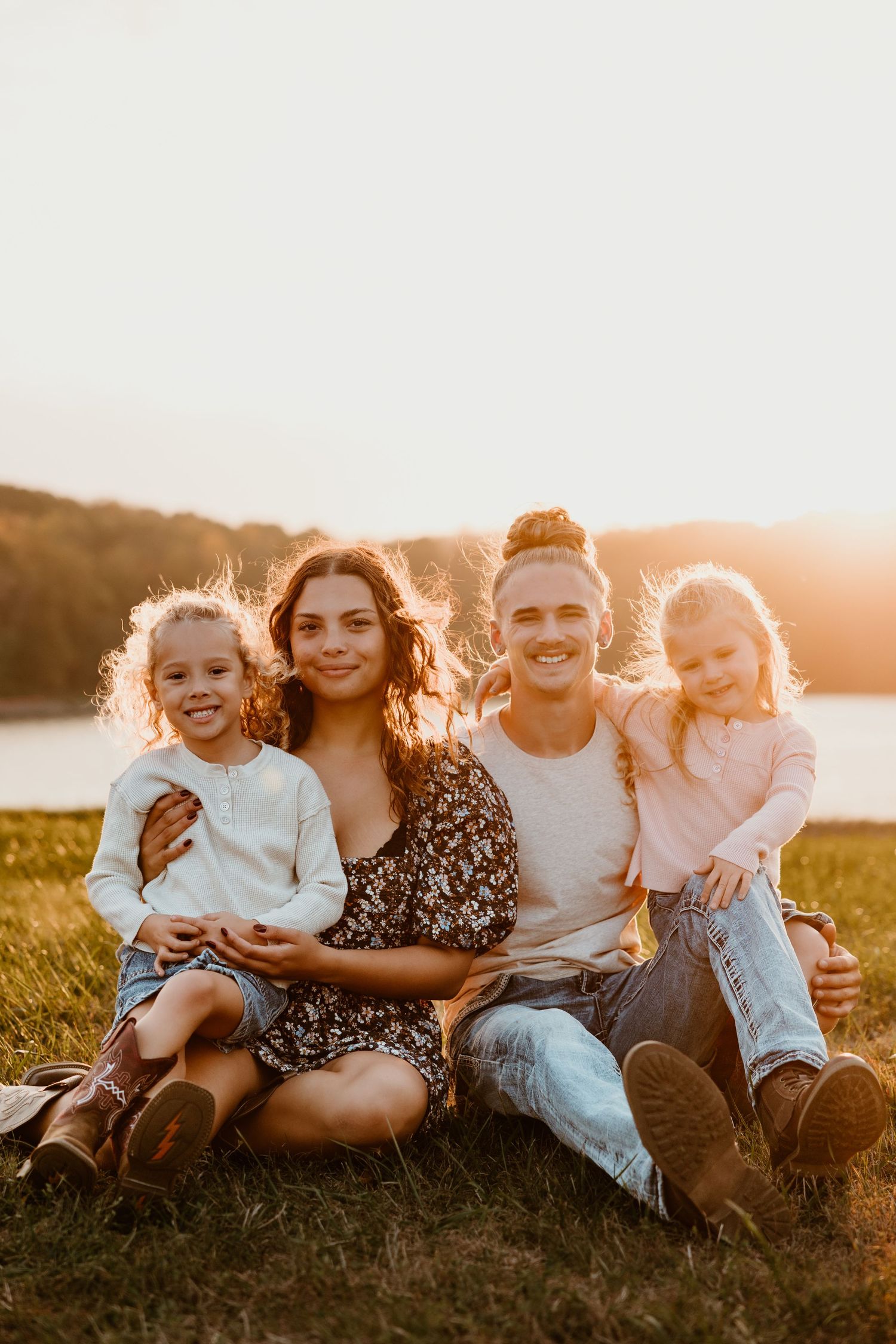 Family sitting together on grass during sunset photoshoot.