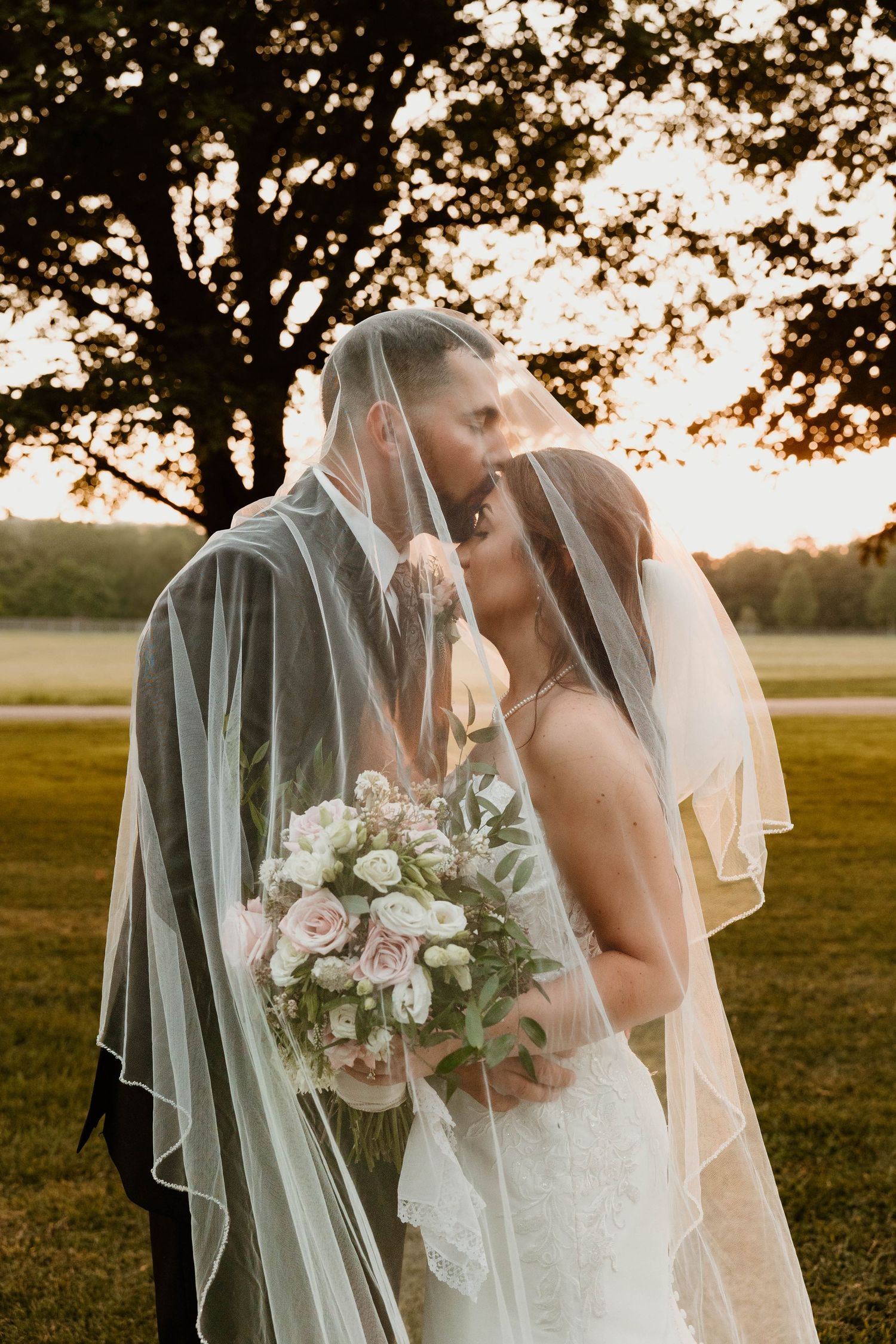 Romantic sunset wedding photos with delicate veils and floral bouquet.