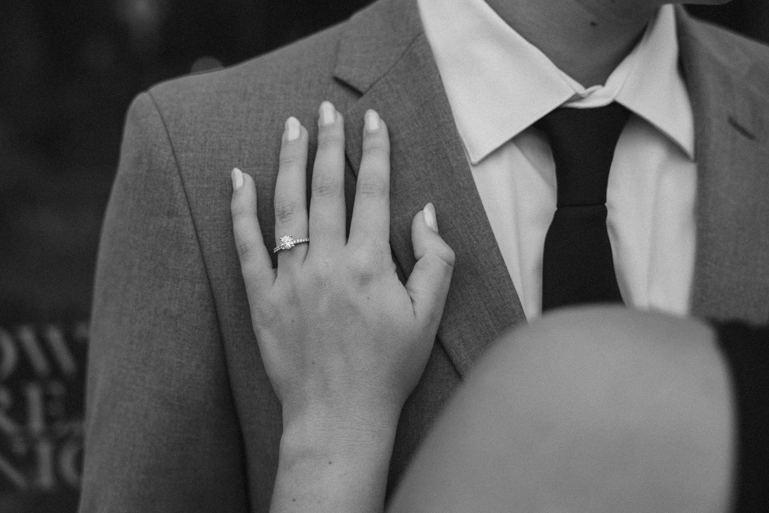 Close-up detail of hands touching a gray suit jacket.