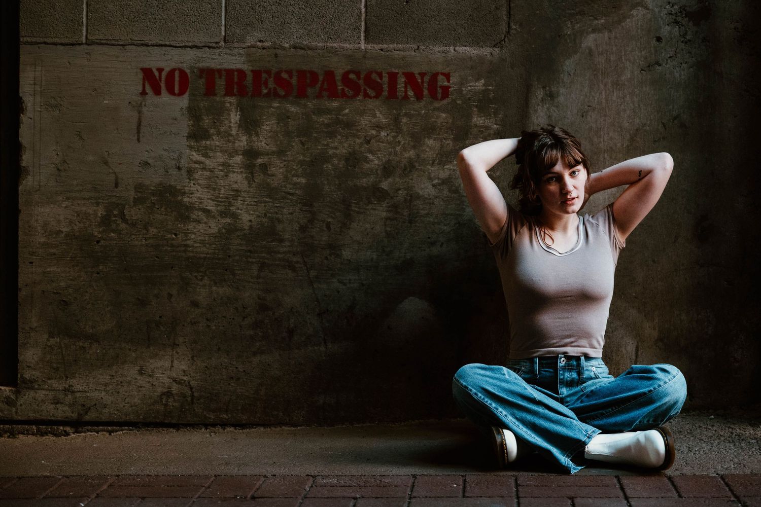 Artistic wall poses against concrete backdrop with 'No Trespassing' sign visible.