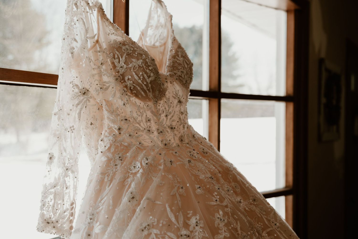 Wedding dress displayed near window creating dramatic silhouette.