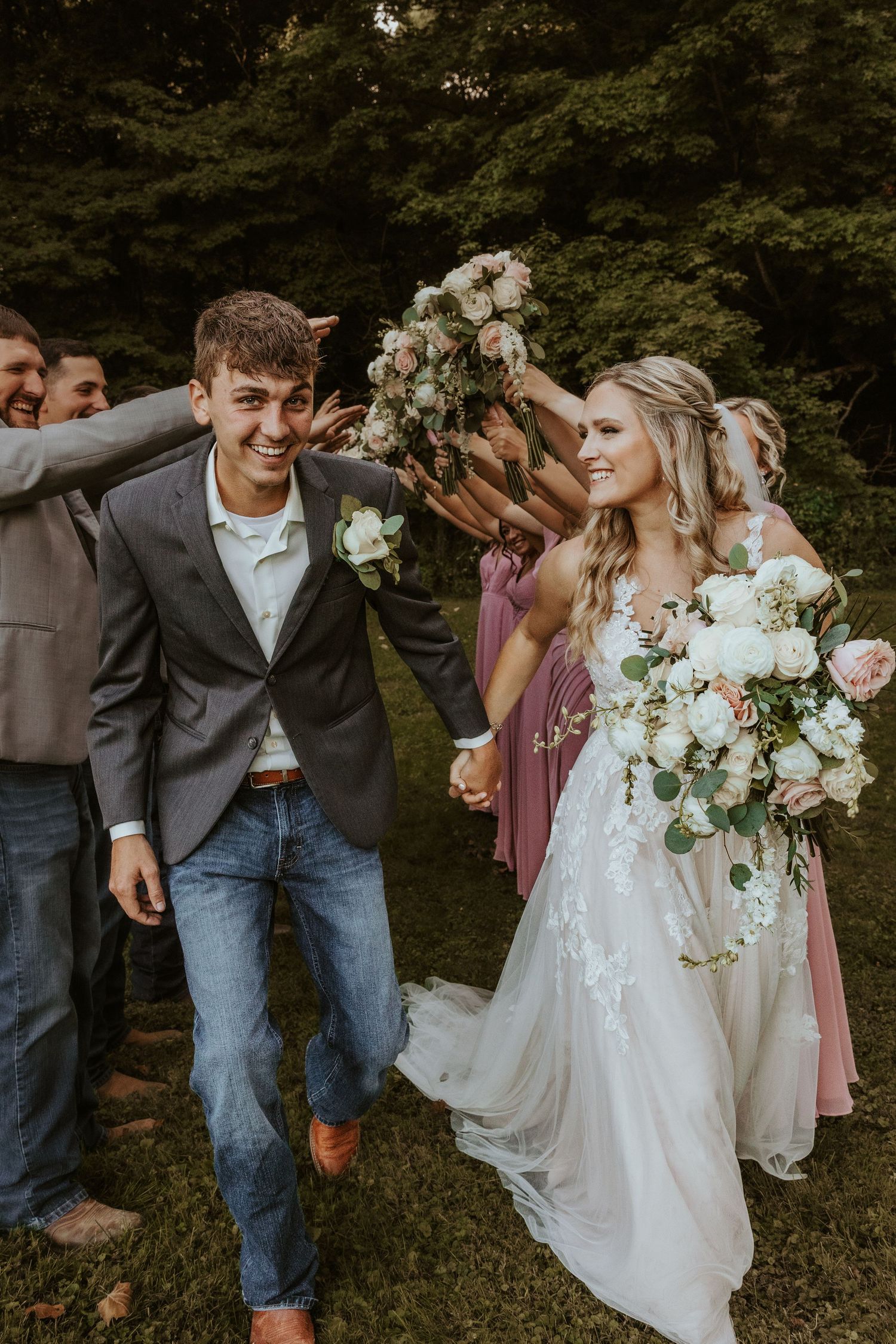 Wedding party celebrates joyfully outdoors with bride in flowing white dress.