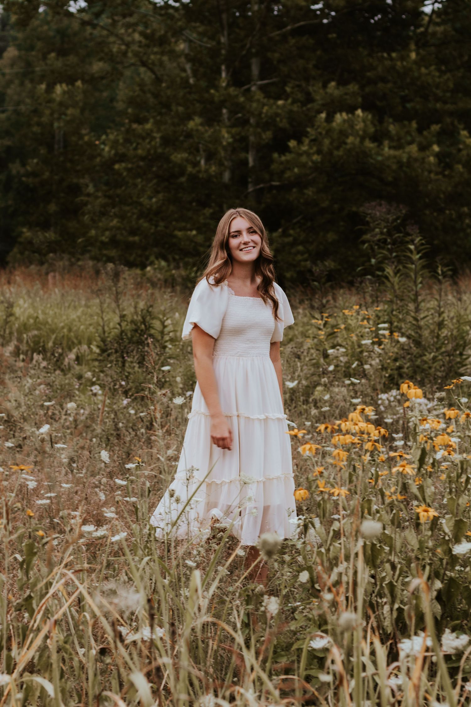 Dreamy summer portrait in a white dress surrounded by wildflowers and natural light.