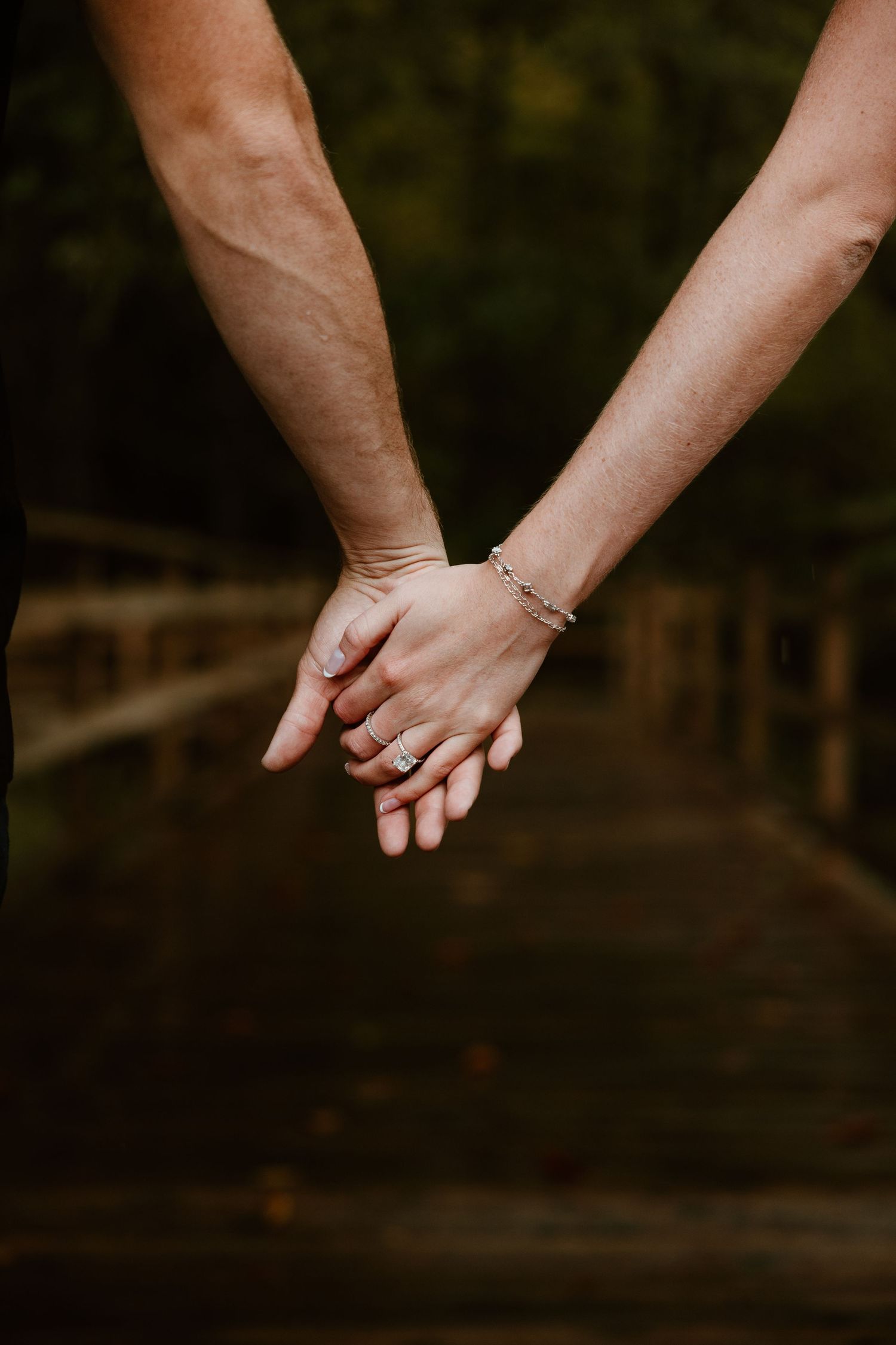 Close-up of two hands holding each other against a dark background.