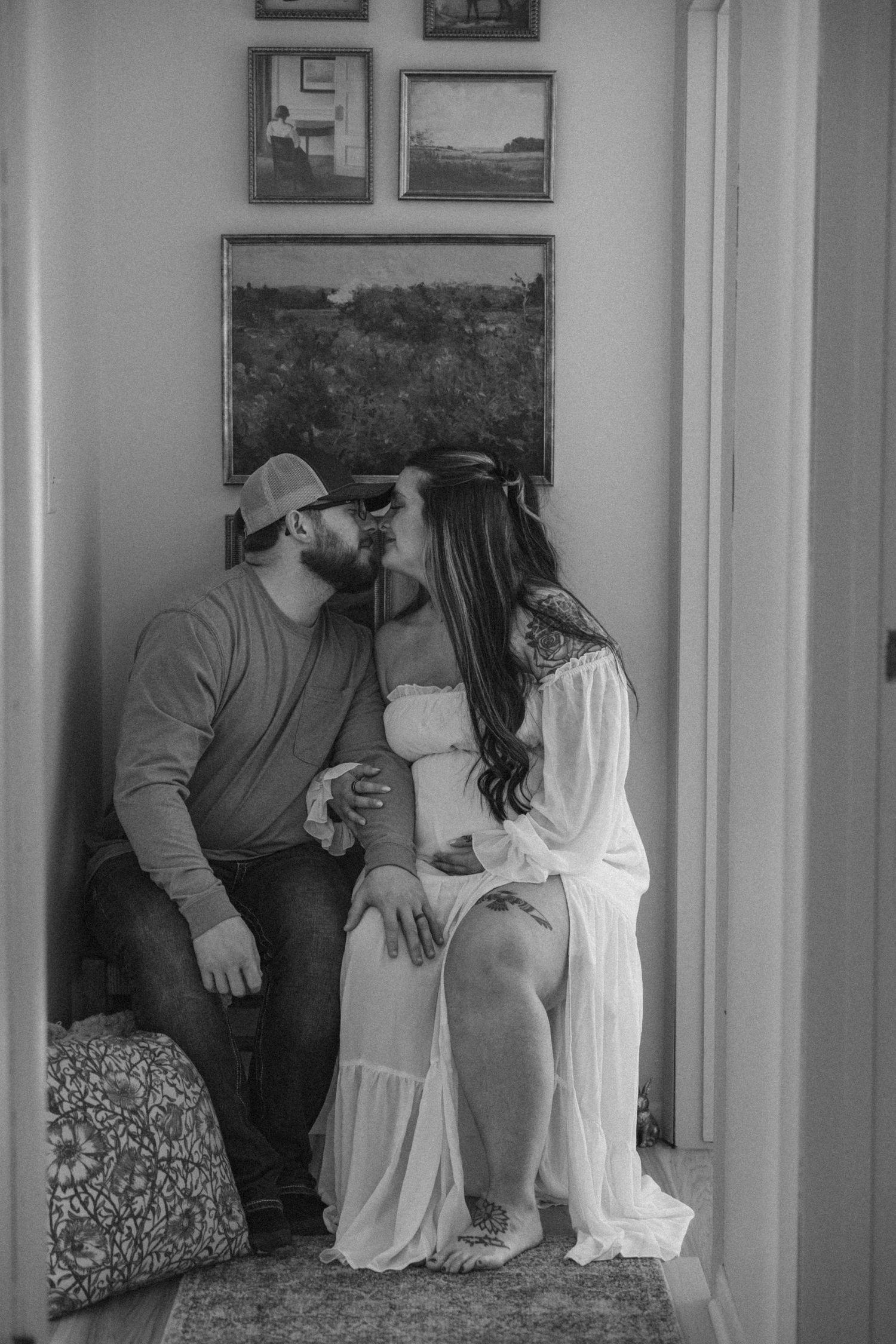 Black and white artistic wedding photograph showing intimate moment between couple in elegant room with framed artwork.