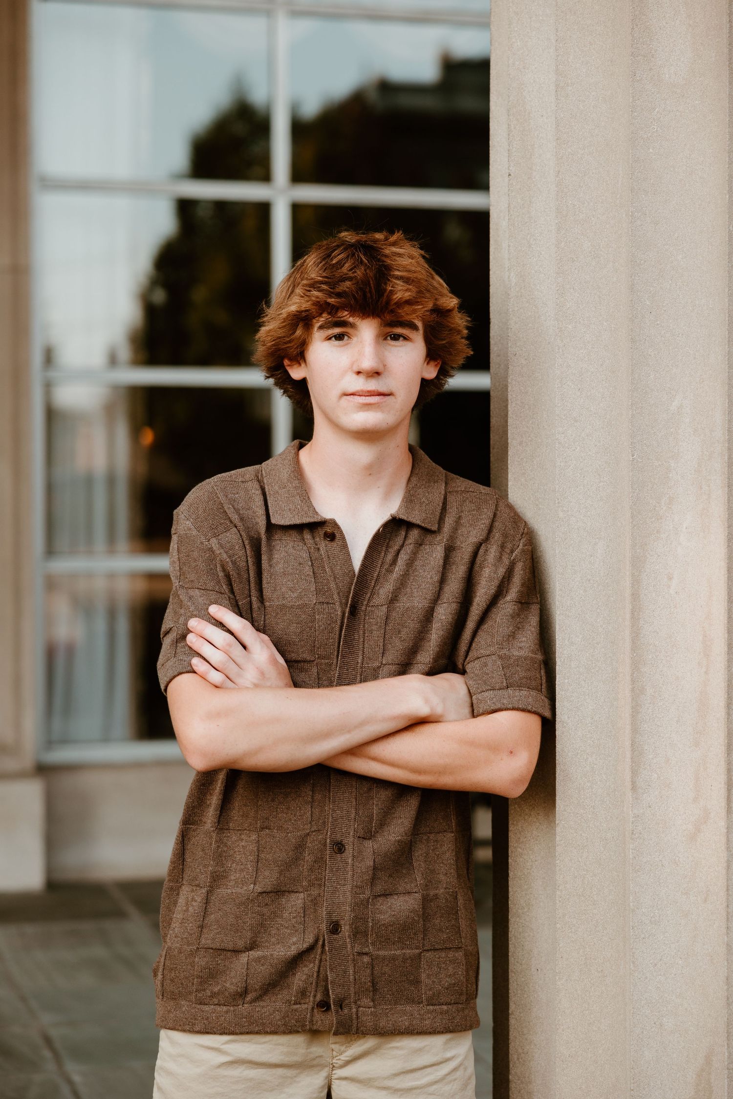Portrait session featuring brown utility jacket against white pillared building exterior.