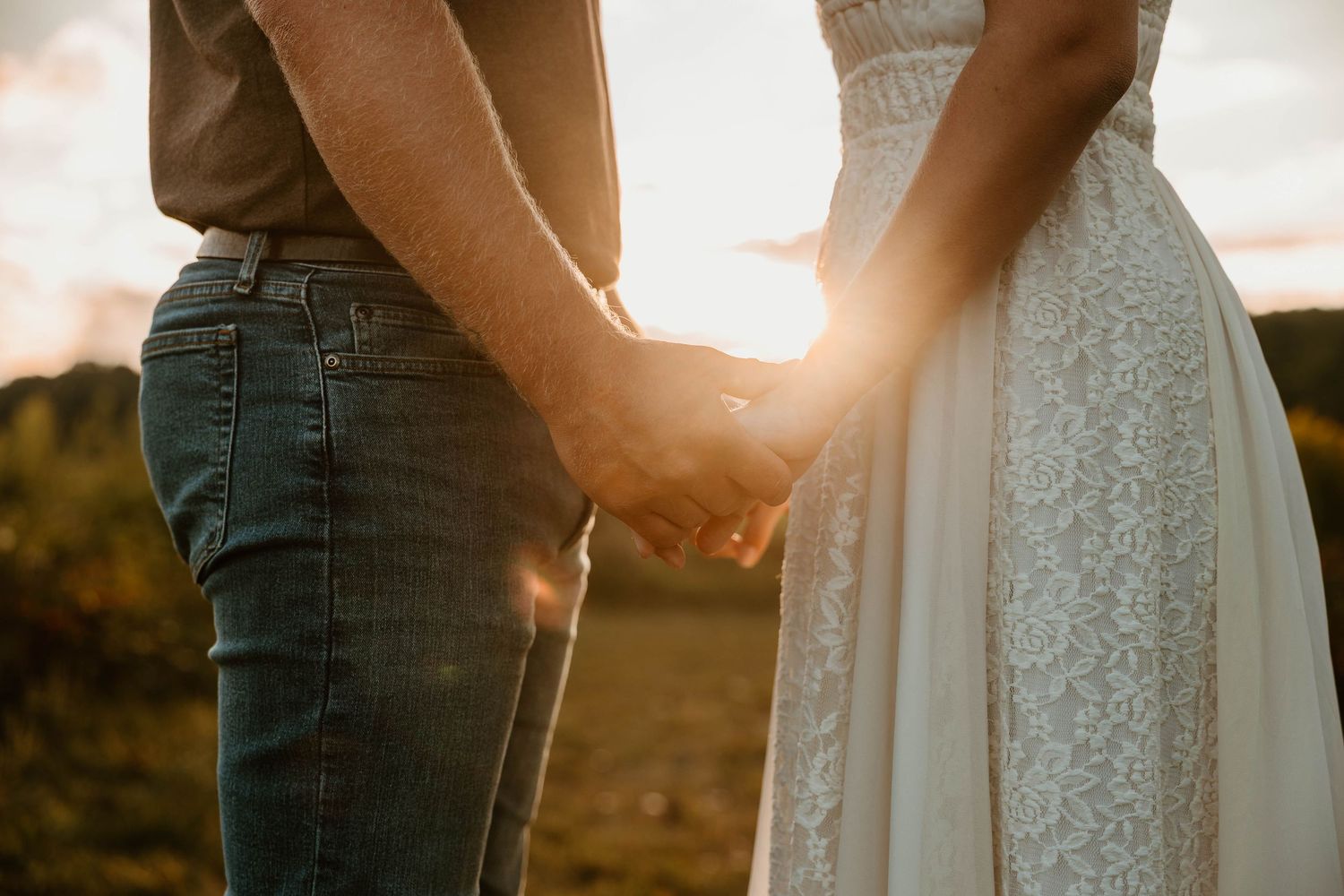 Couple holding hands in sunset light wearing casual attire.