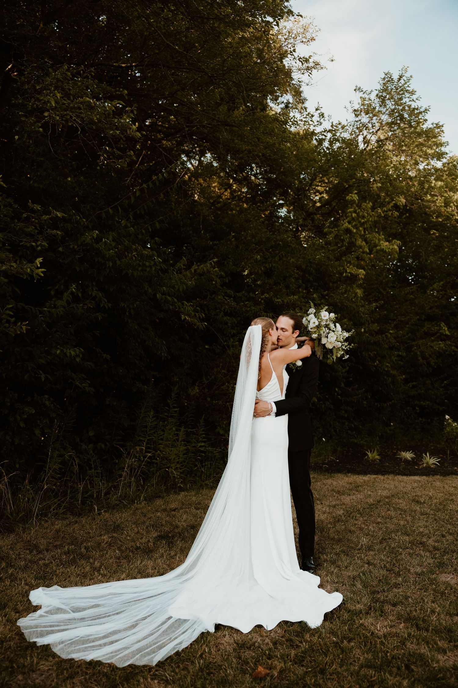 A romantic sunset wedding portrait shows a couple embracing in a field.