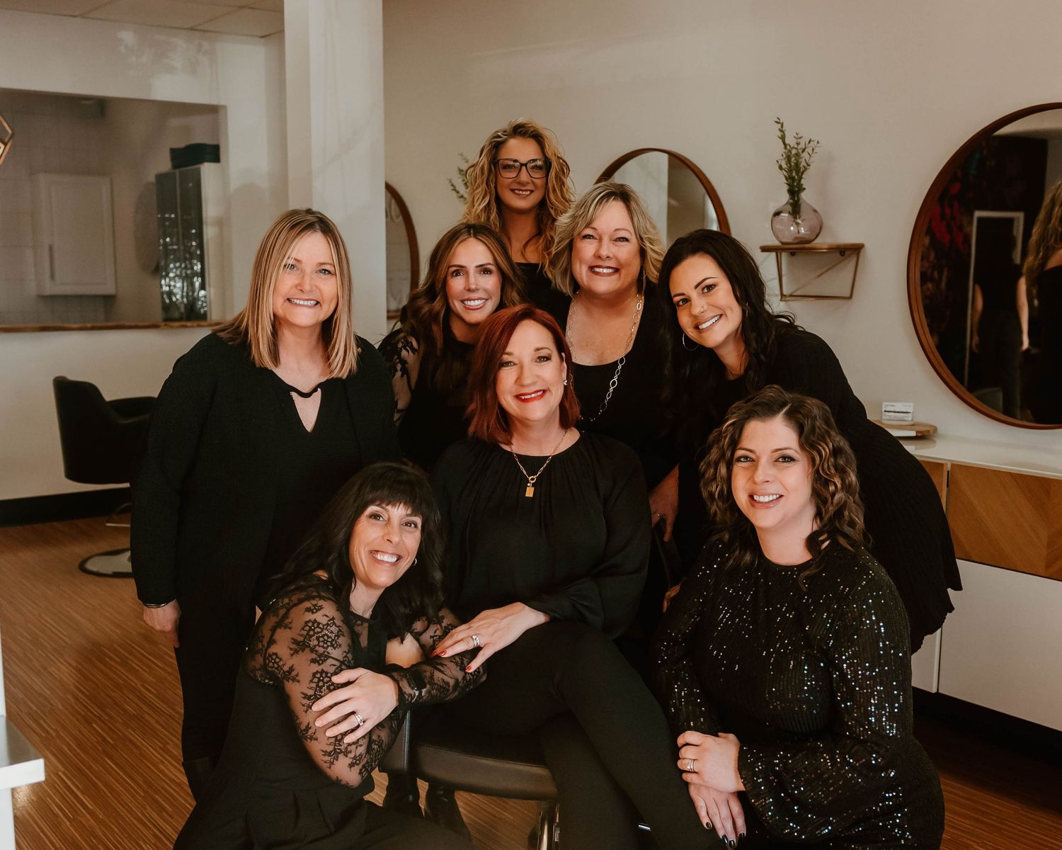 Group photo of salon team members wearing black in modern spa interior.