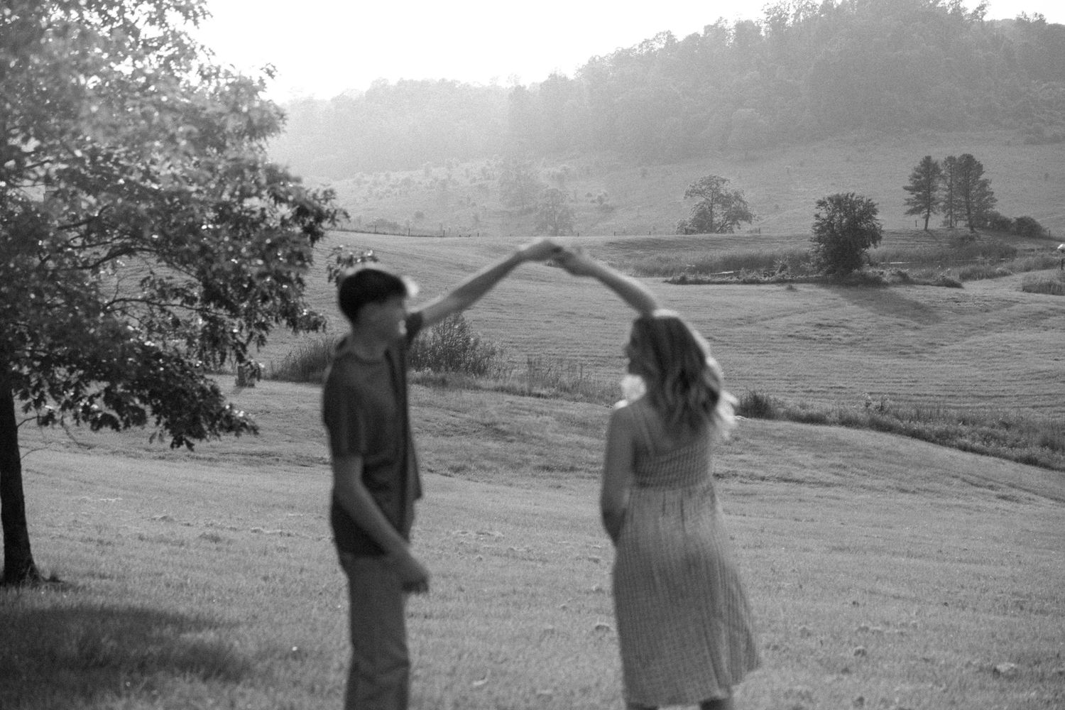A black and white photo captures a couple's silhouettes against a rural landscape.