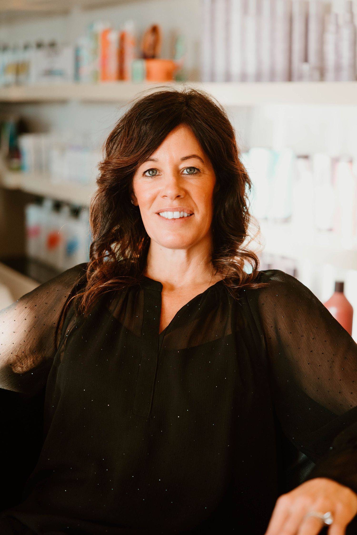 Series of headshots featuring dark-haired professional in black attire against blurred salon background.