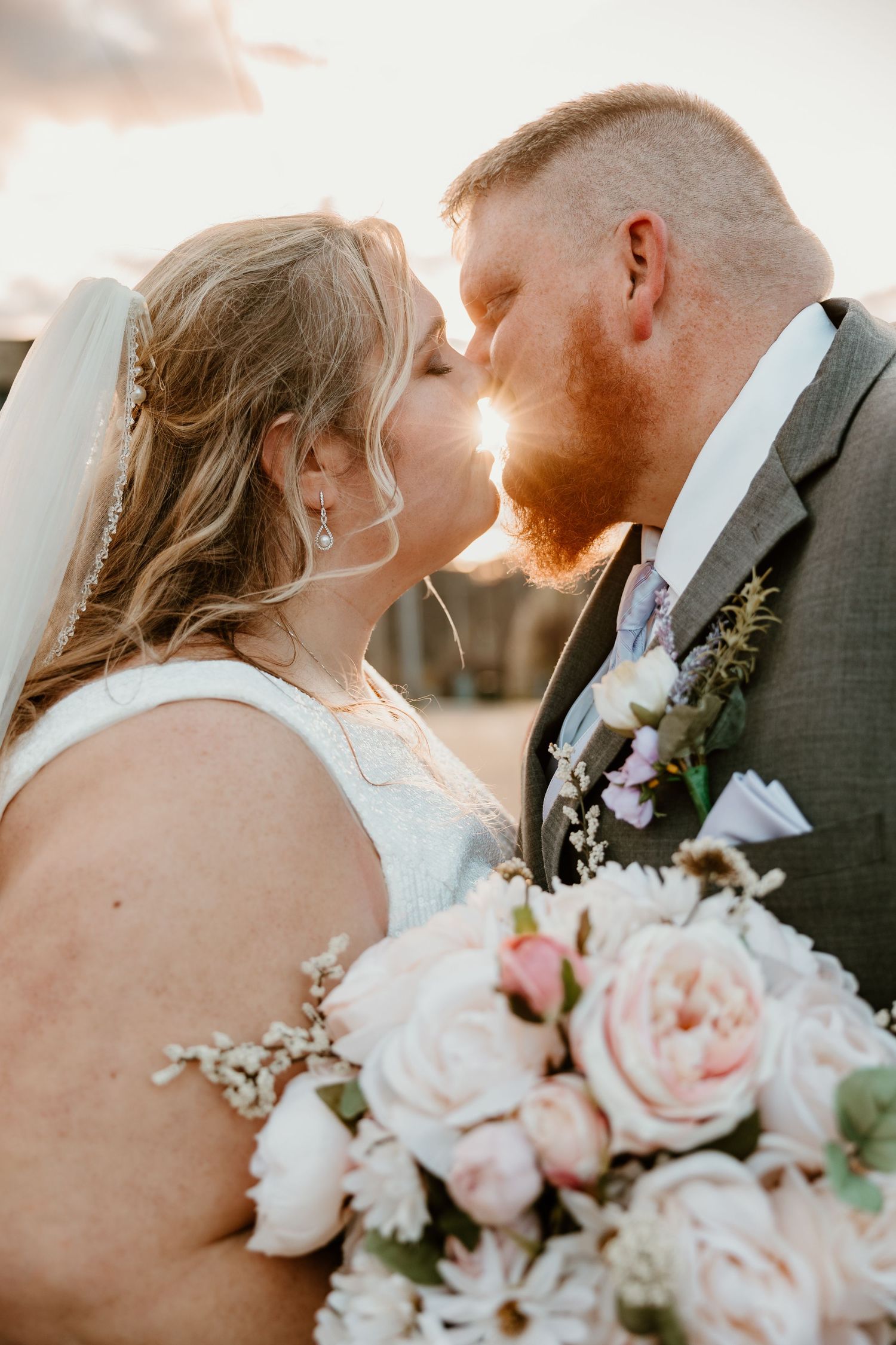 Romantic sunset wedding portrait with pink and white floral bouquet.