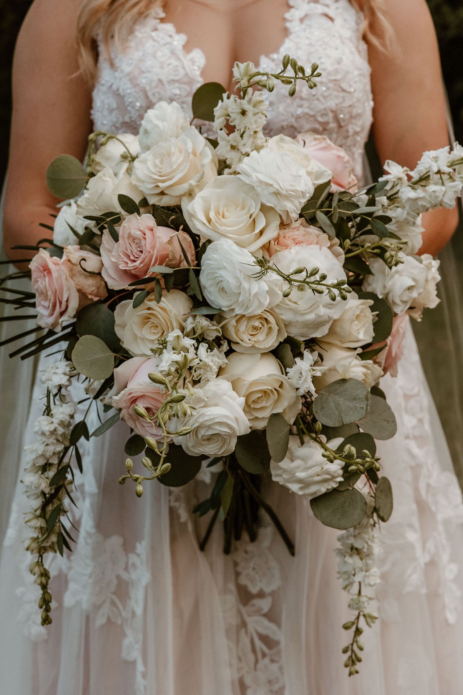 Row of elegant white and blush pink wedding bouquets with roses and greenery.