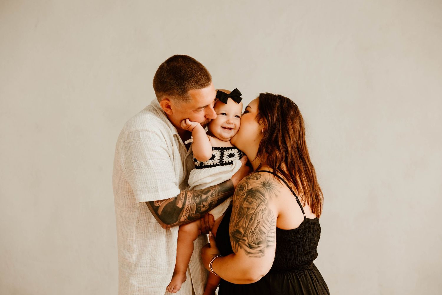 A couple in formal attire embraces and kisses in a romantic photoshoot series.