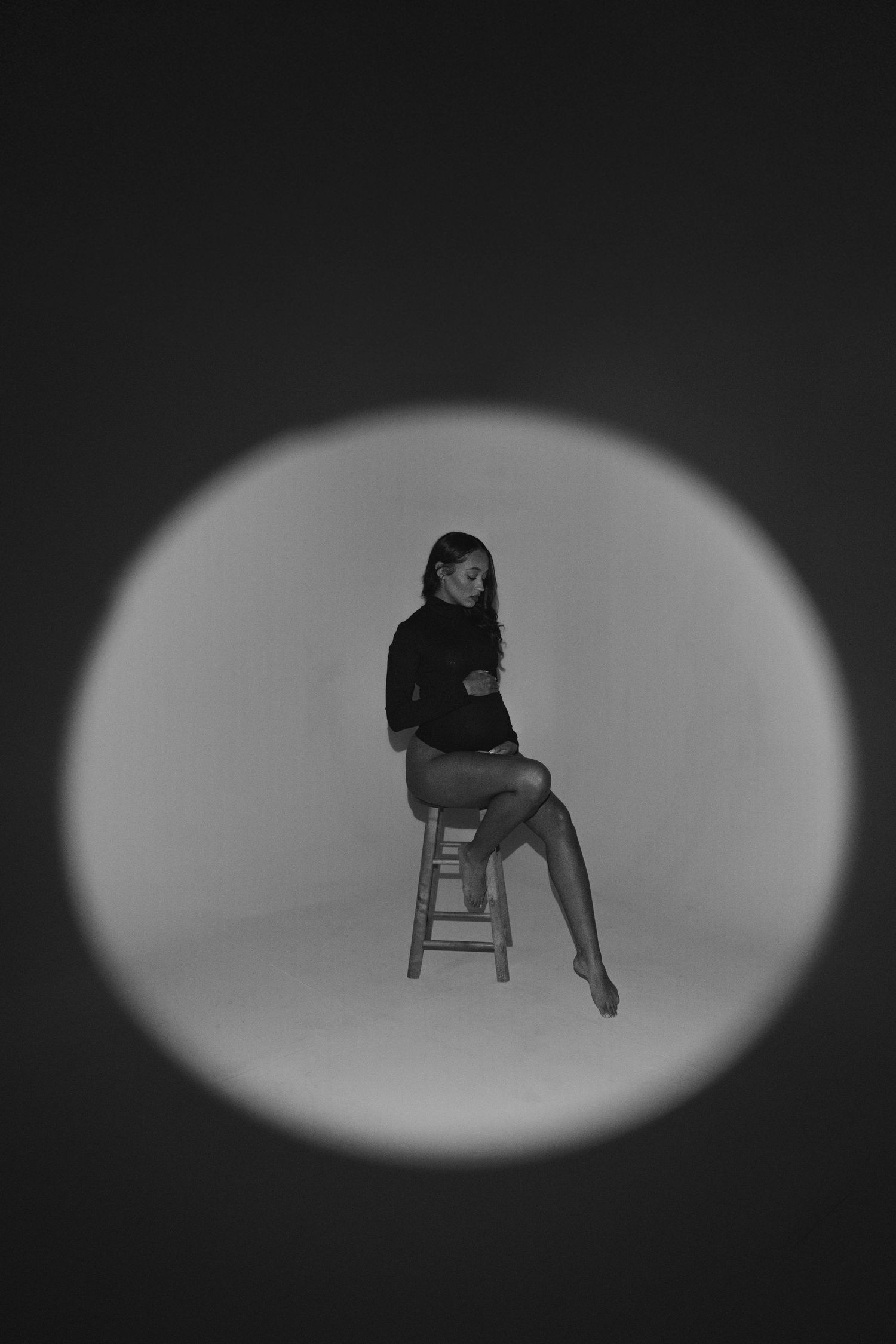A series of silhouetted figures seated on chairs against a dark background with dramatic spotlighting.