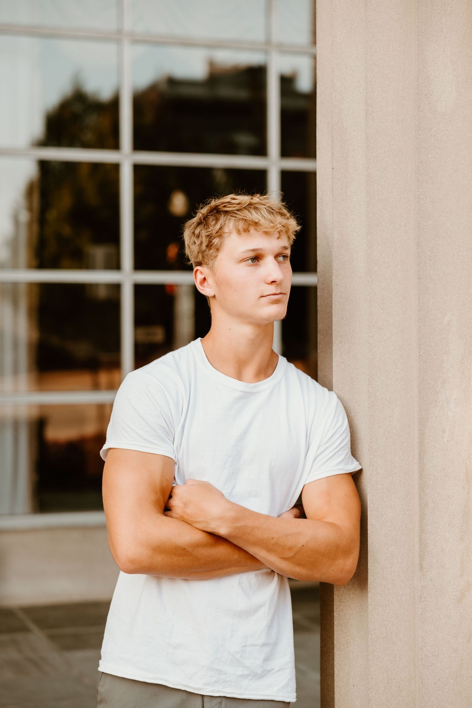 Architectural portrait against white pillars and windows wearing basic white t-shirt.