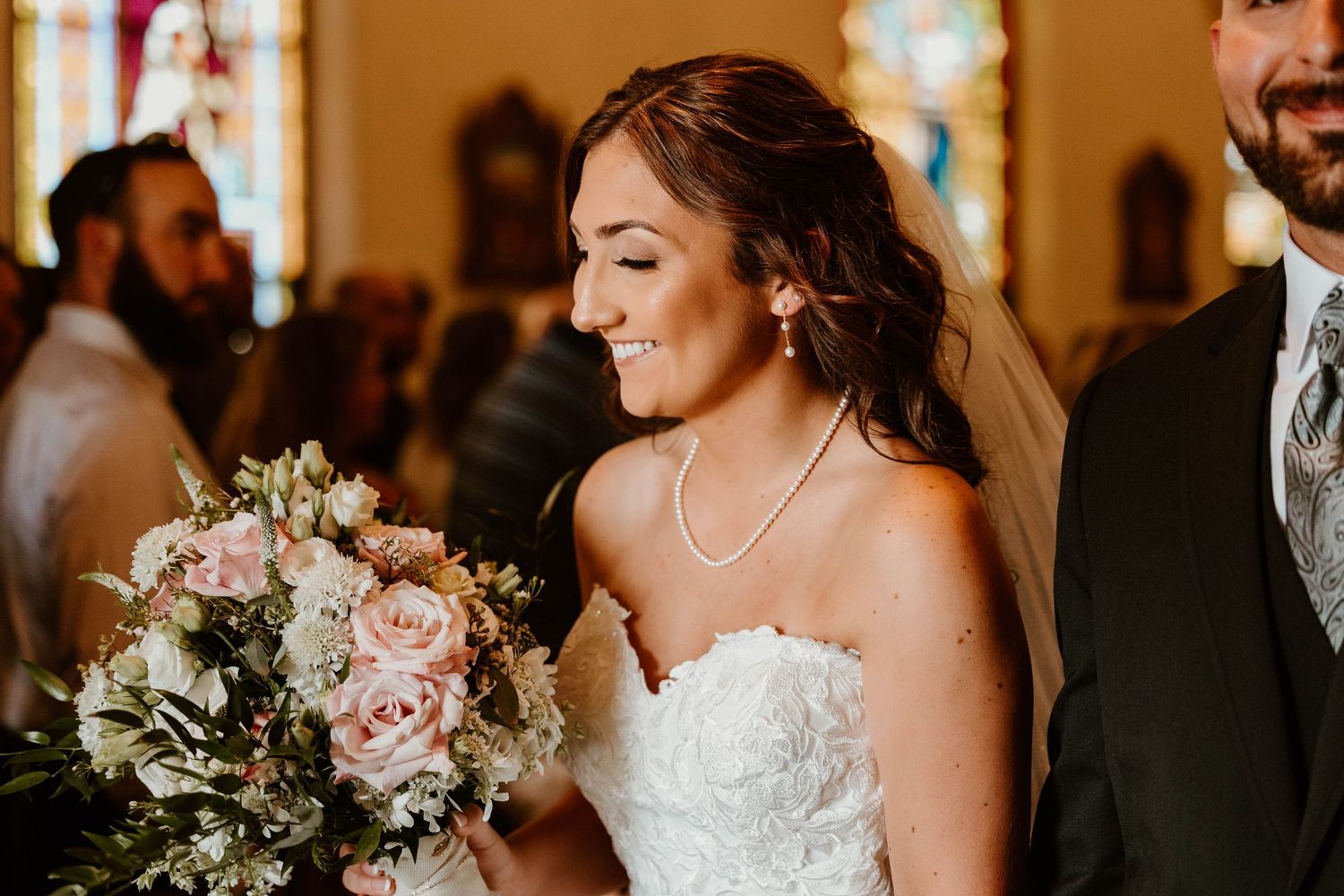 Wedding ceremony inside a church with stained glass windows and elegant floral arrangements.