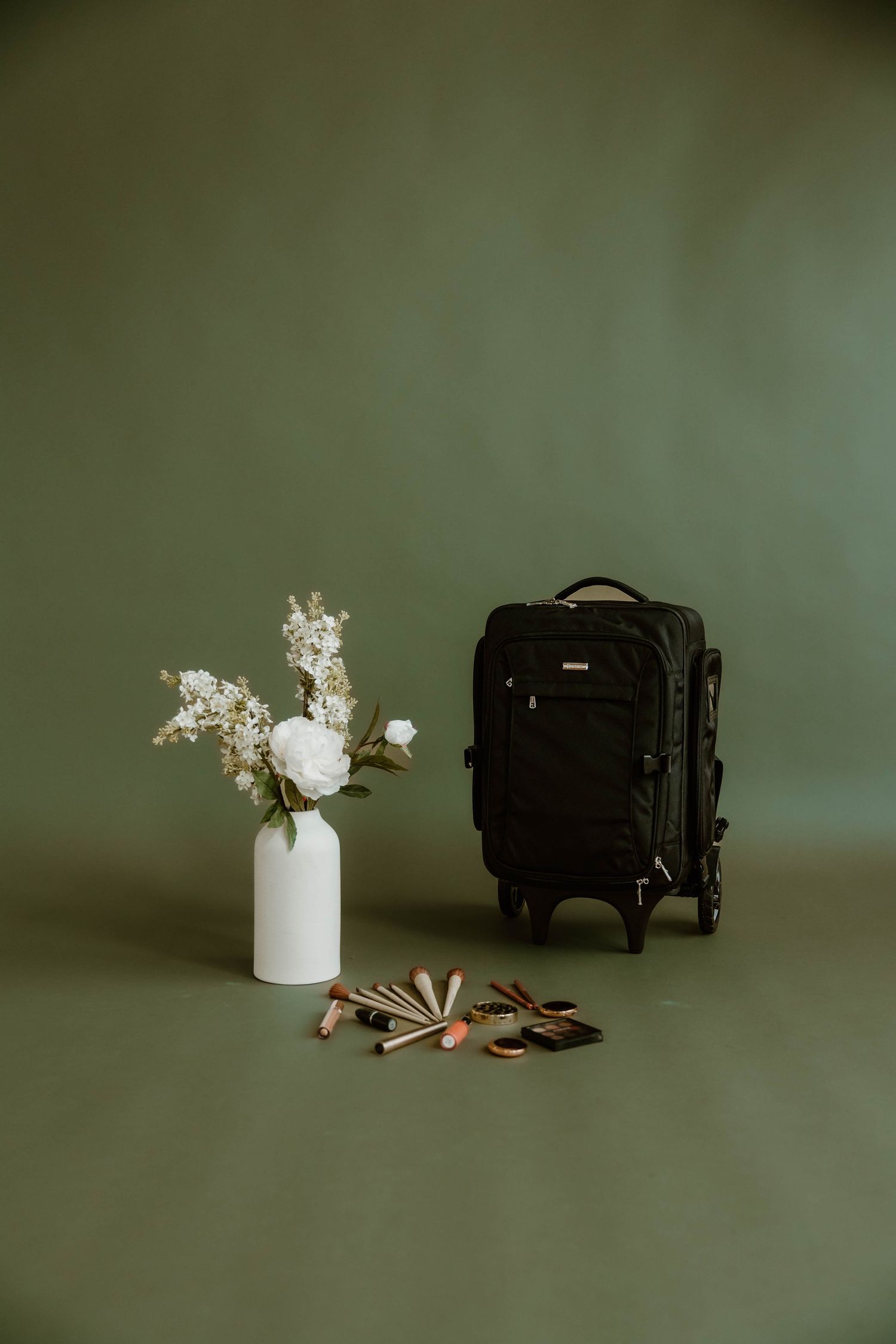 Still life arrangement with white flowers in a vase and vintage camera equipment against a dark background.